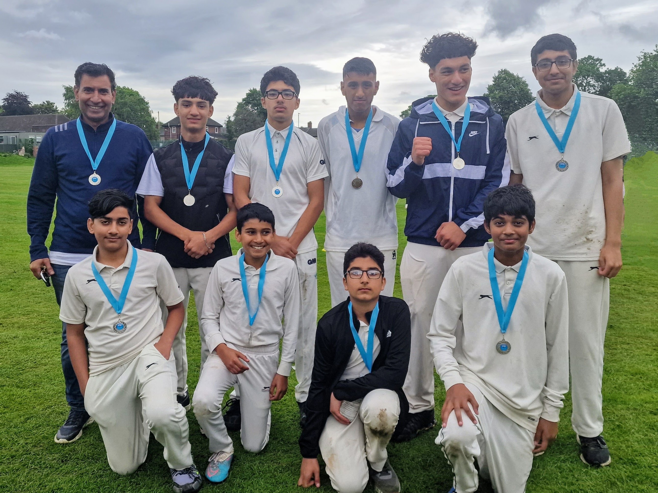Shiregreen Cricket Club junior team with coach Banaras Ali, proudly posing with their medals after the Junior Hundred tournament.