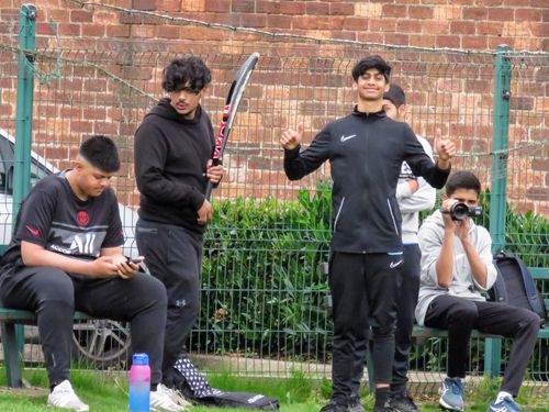 Players getting ready before the game — smiling, holding bats, and testing the camera on the sidelines before play begins.