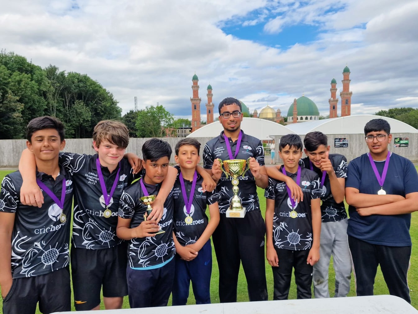 Sheffield team celebrate becoming Yorkshire Junior Hundred 2023 champions at Park Avenue, Bradford — captain holds the trophy high as teammates stand arm in arm, showing unity, friendship, and success.