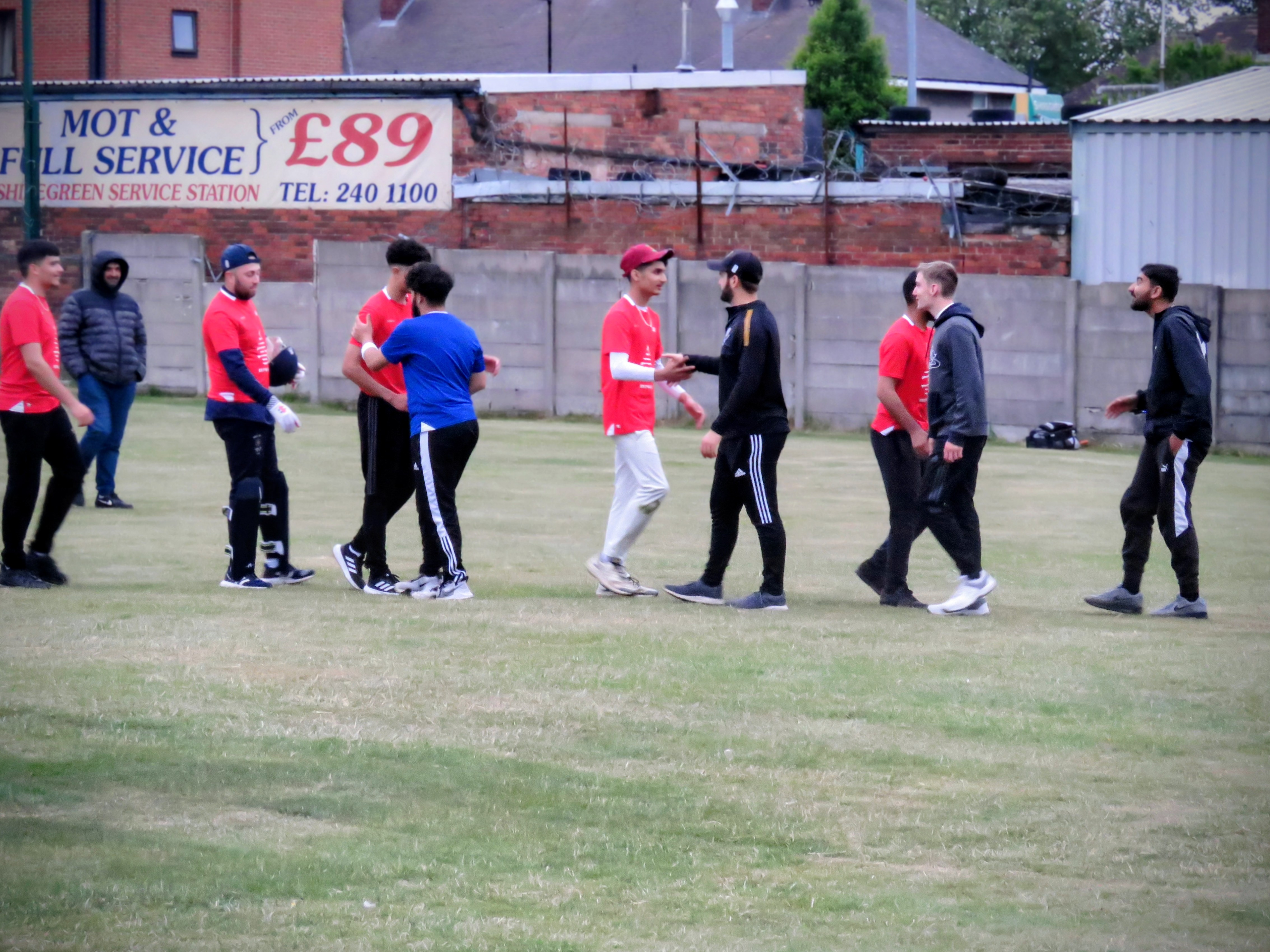 Players from both teams shake hands after the match, showing respect and sportsmanship in the Red v Blue Youth Hundred.