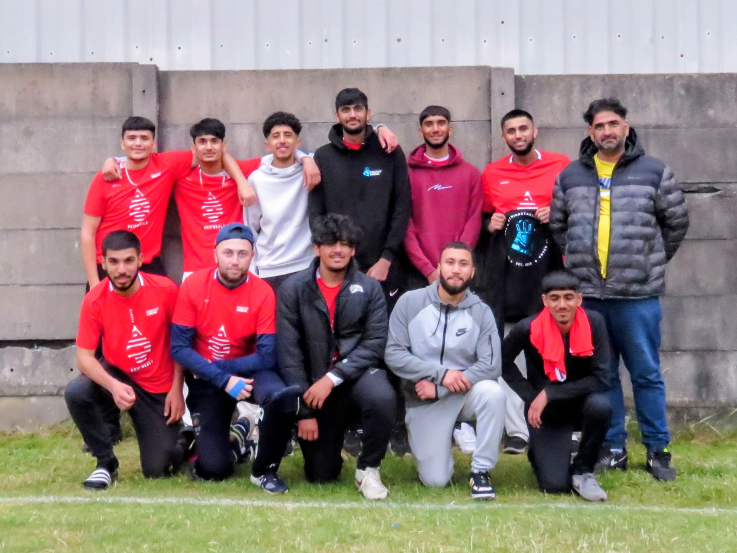 Red team of under-21 players pose for a team photo in Cricket Arena kits, celebrating youth unity and friendship.