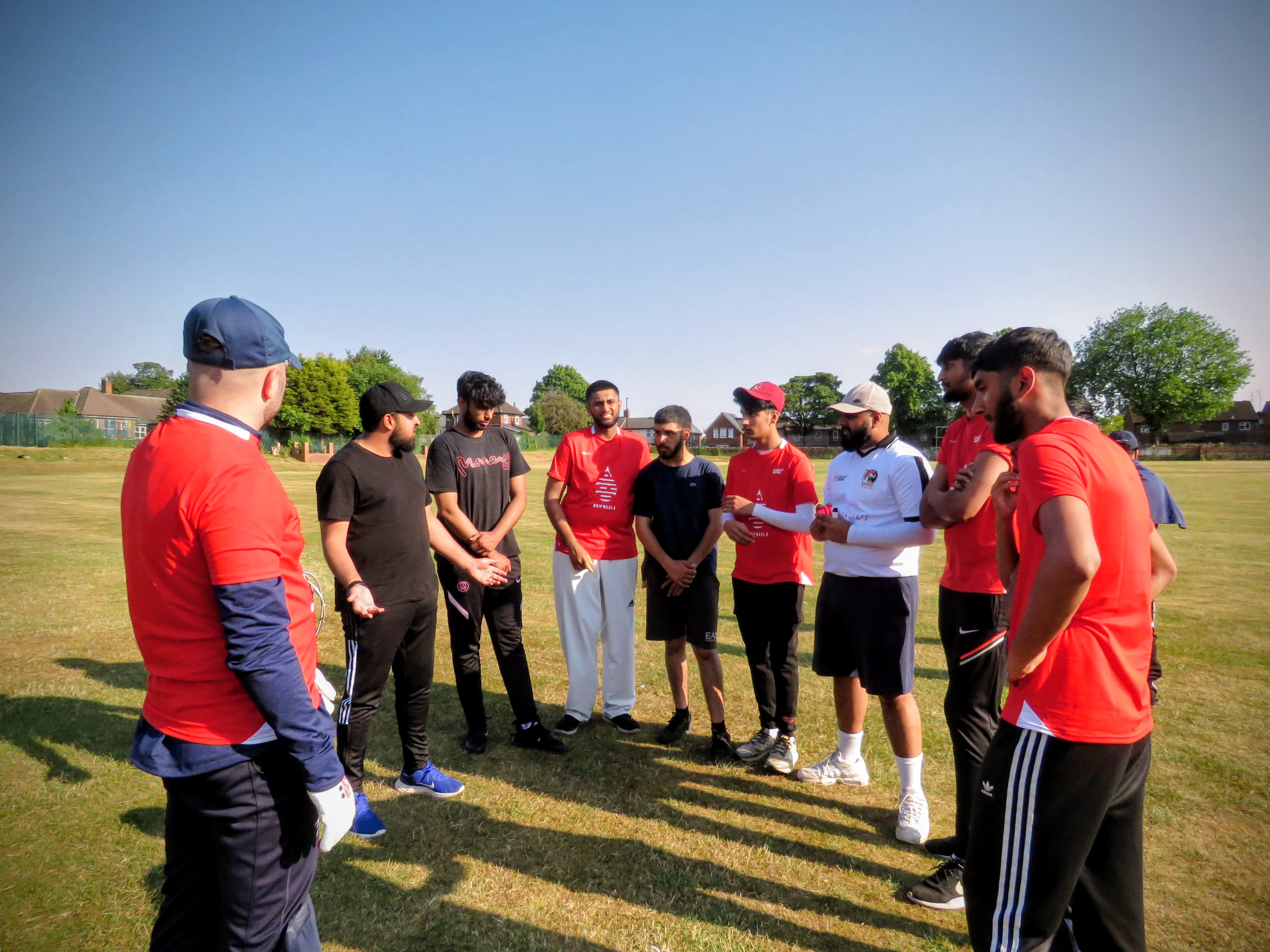 Team Red listen to their captain and volunteer coach discuss tactics and positive mindset at Shiregreen Cricket Club.
