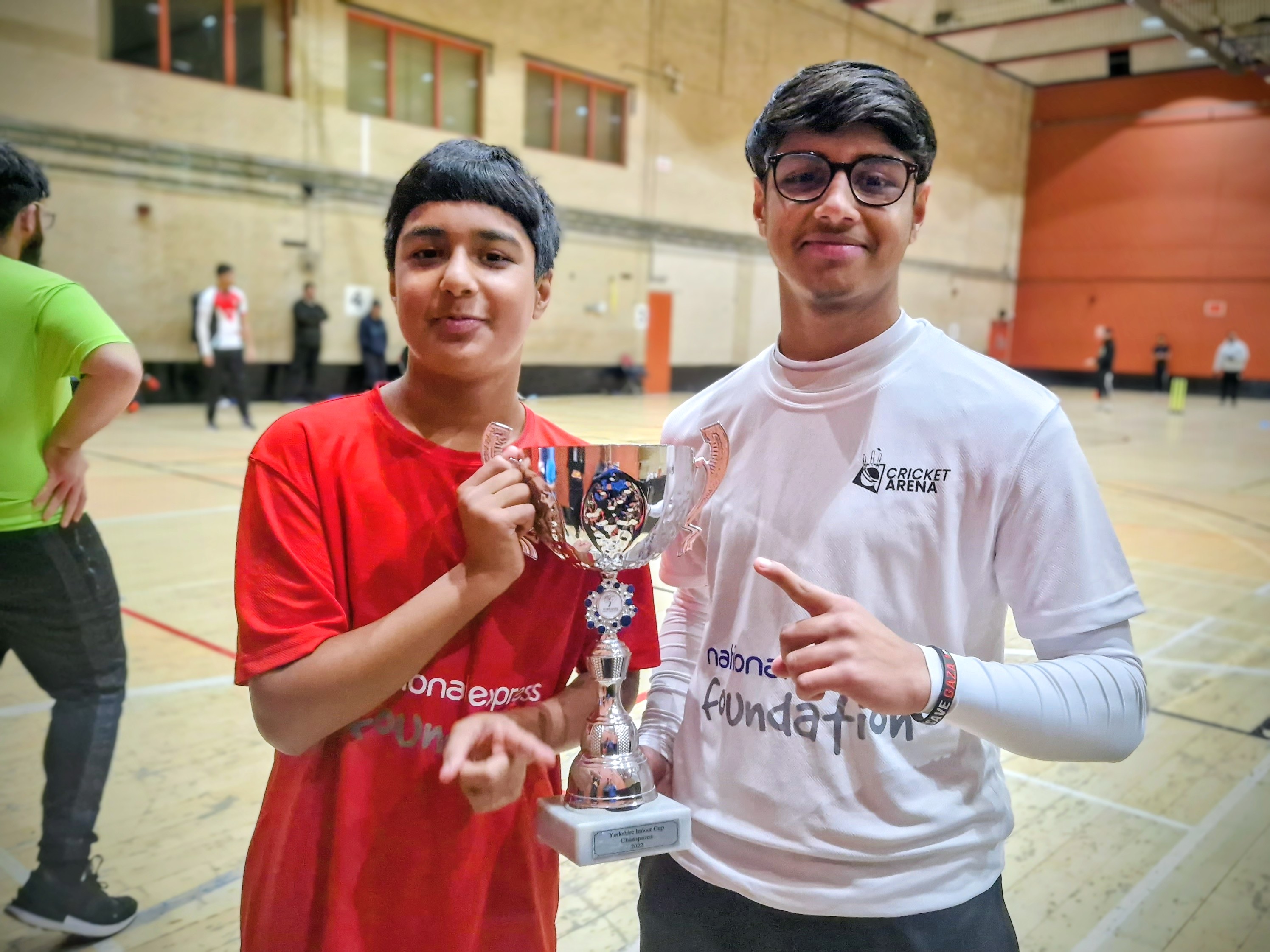 Two MBL 2023 players proudly hold the champions’ trophy at Concord Sports Centre, celebrating youth indoor cricket success.