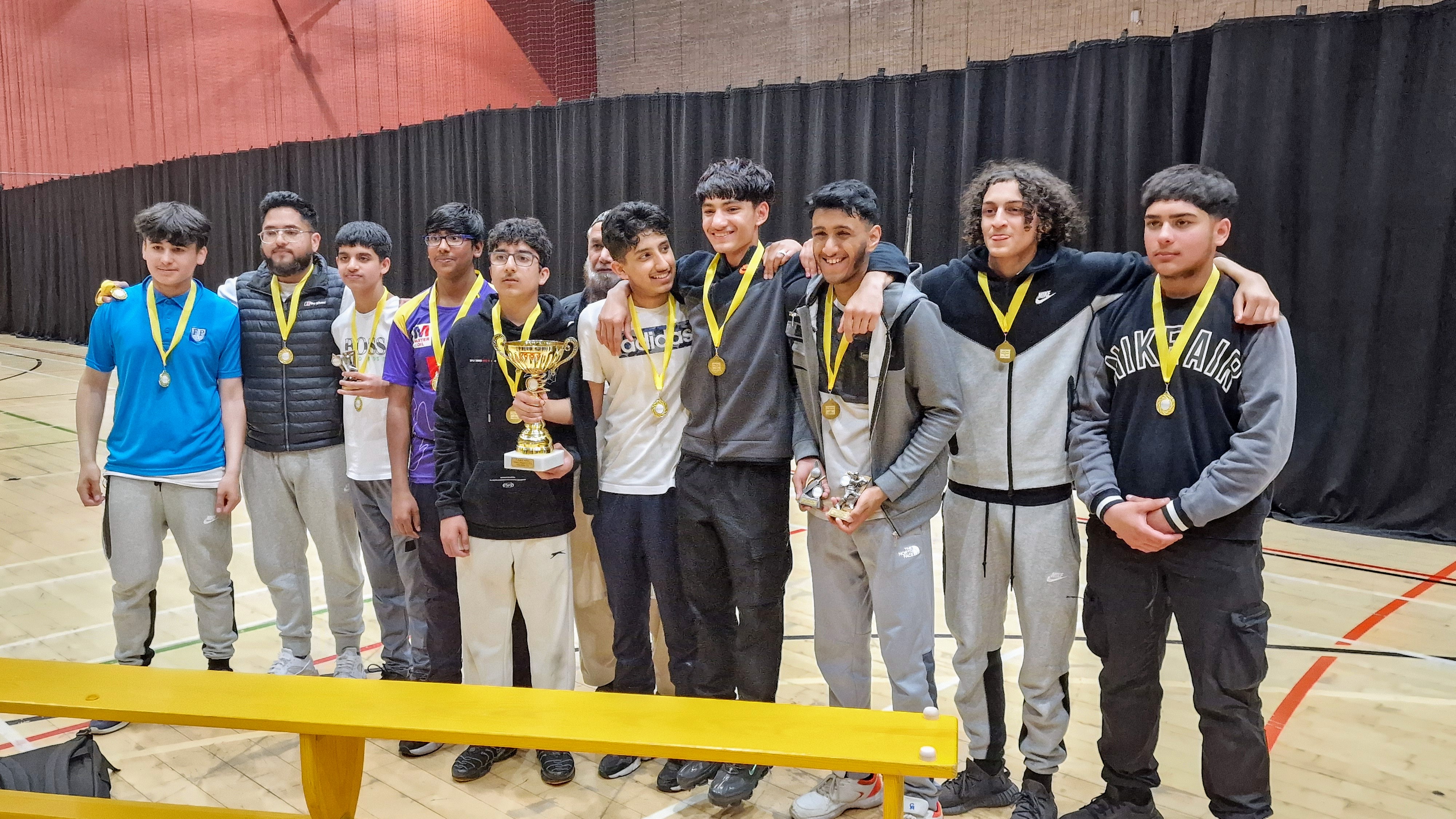 Saalik Youth celebrate at Concord after winning the Central Co-op Junior Hundred 2024, holding the trophy and wearing medals.