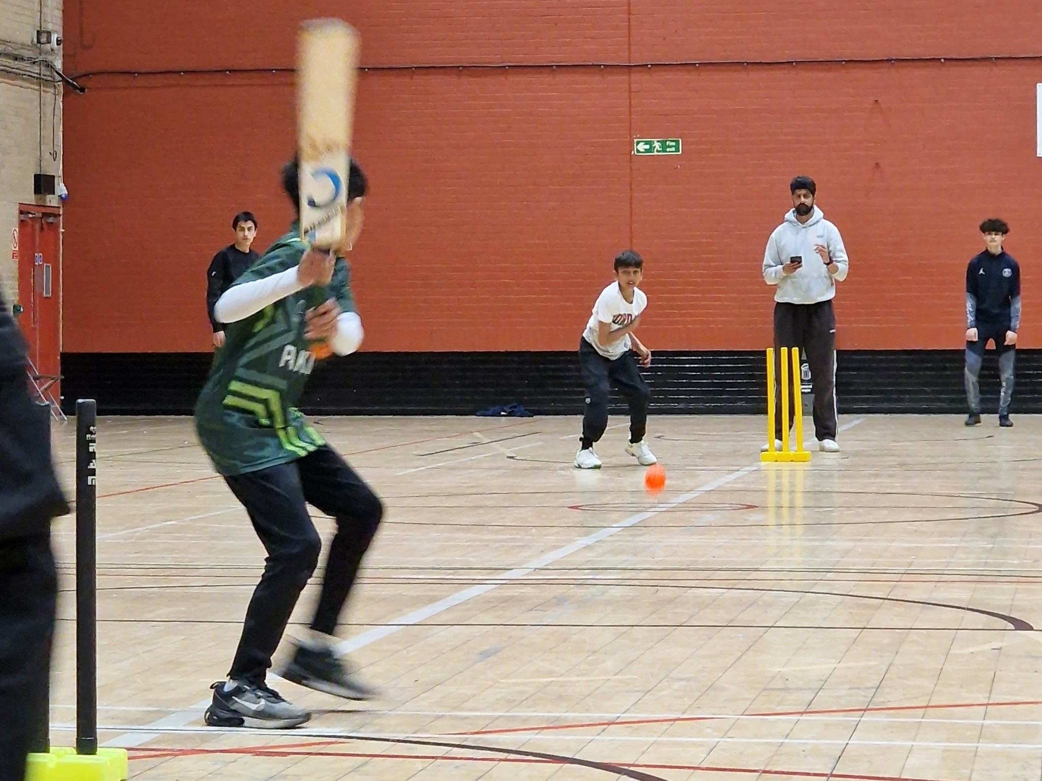 Indoor windball bowler sends down the orange ball as the batter sets at Concord sports hall.