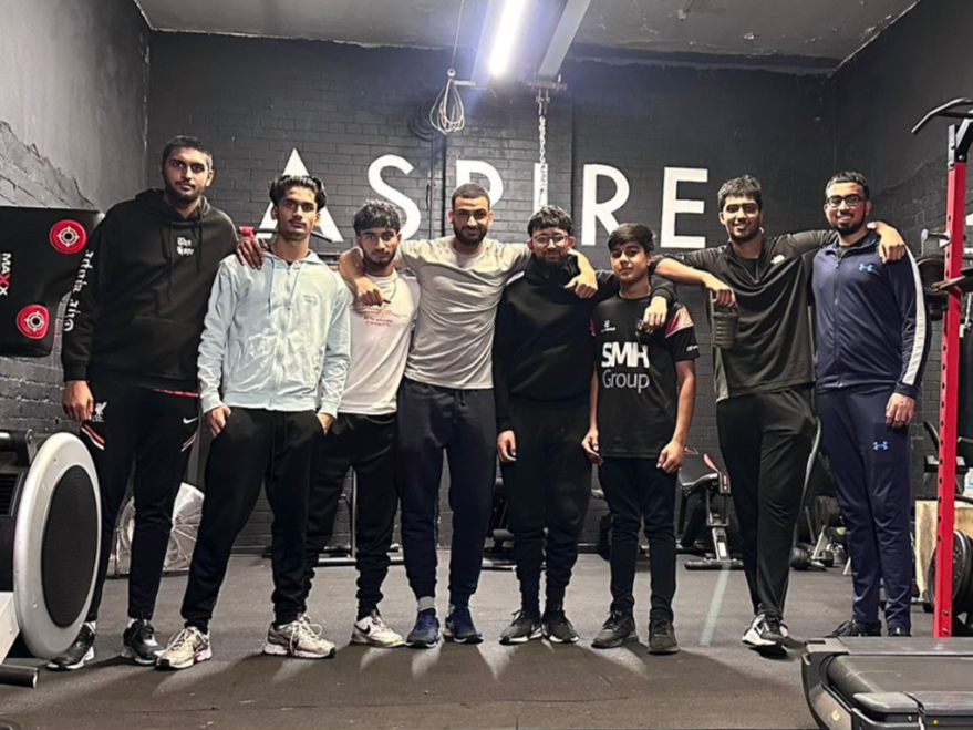 Group of young men from Cricket Arena Youth Sports Club with Aspire 1 coach Mazen after a fitness workshop in a Sheffield gym.