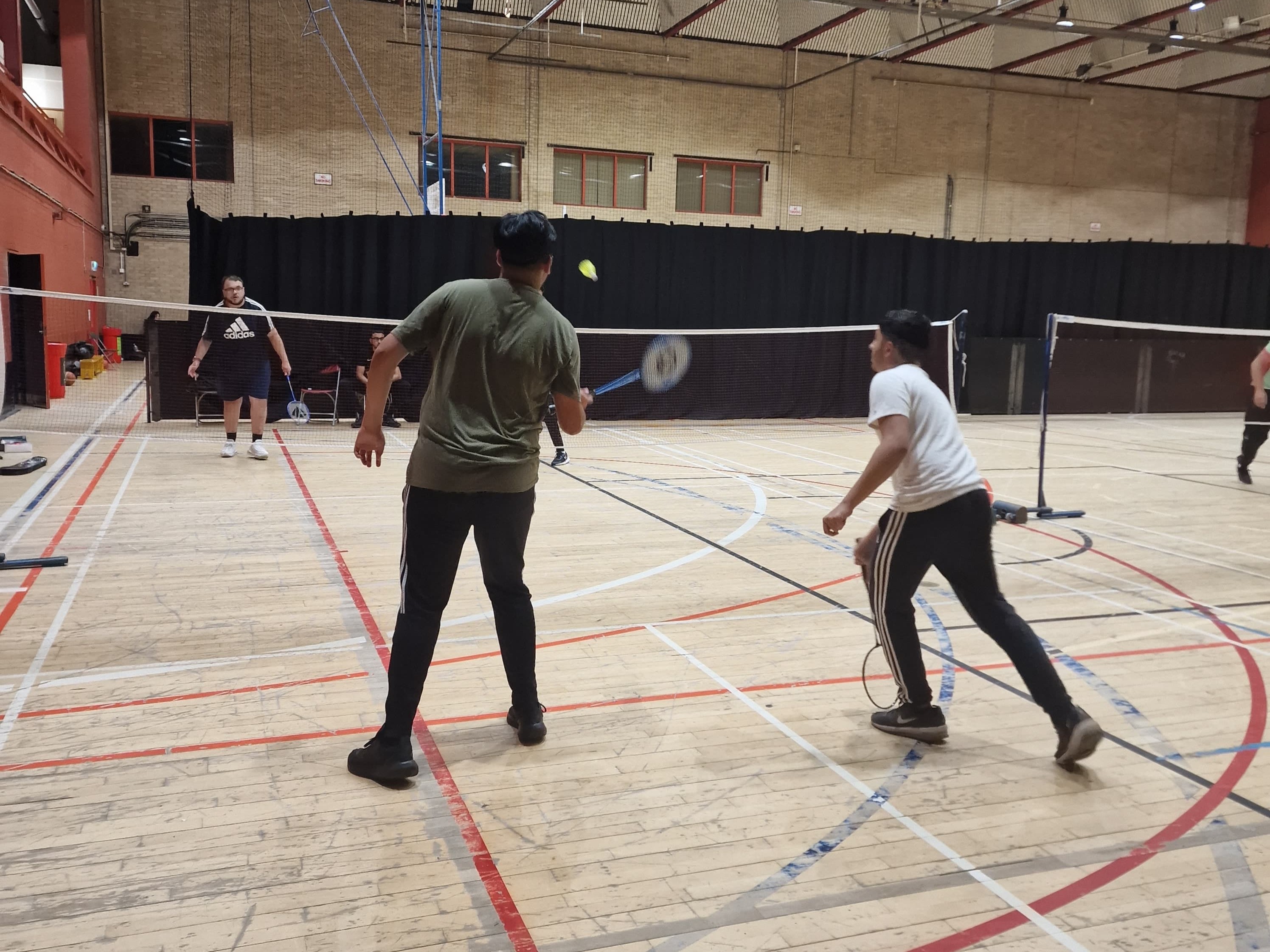 Two young men playing badminton in a mixed-sport Youth Sports Club session at Concord Sports Centre in Sheffield.