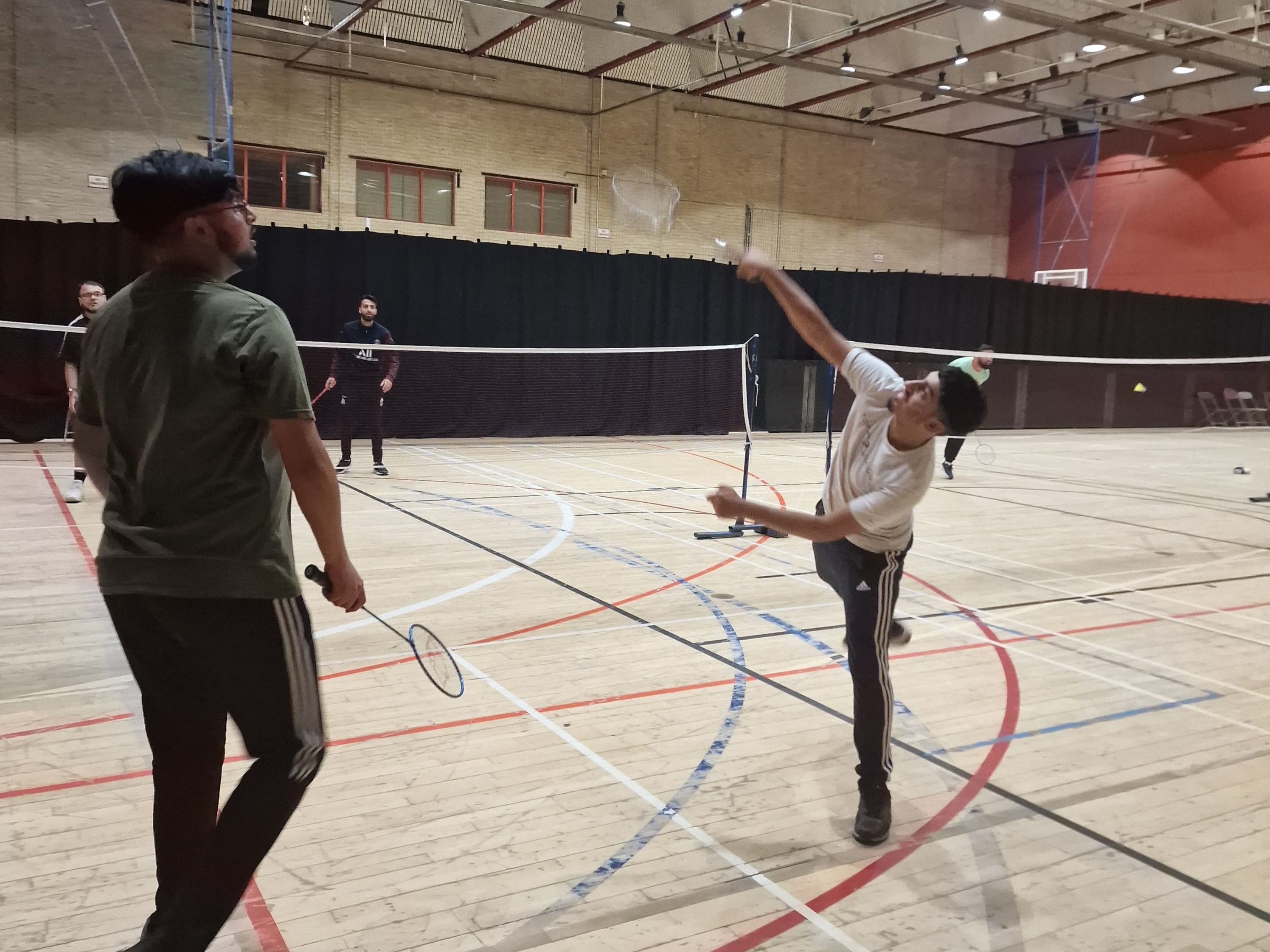 Young player jumping to play a badminton smash during a mixed-sport Youth Sports Club session at Concord Sports Centre in Sheffield.
