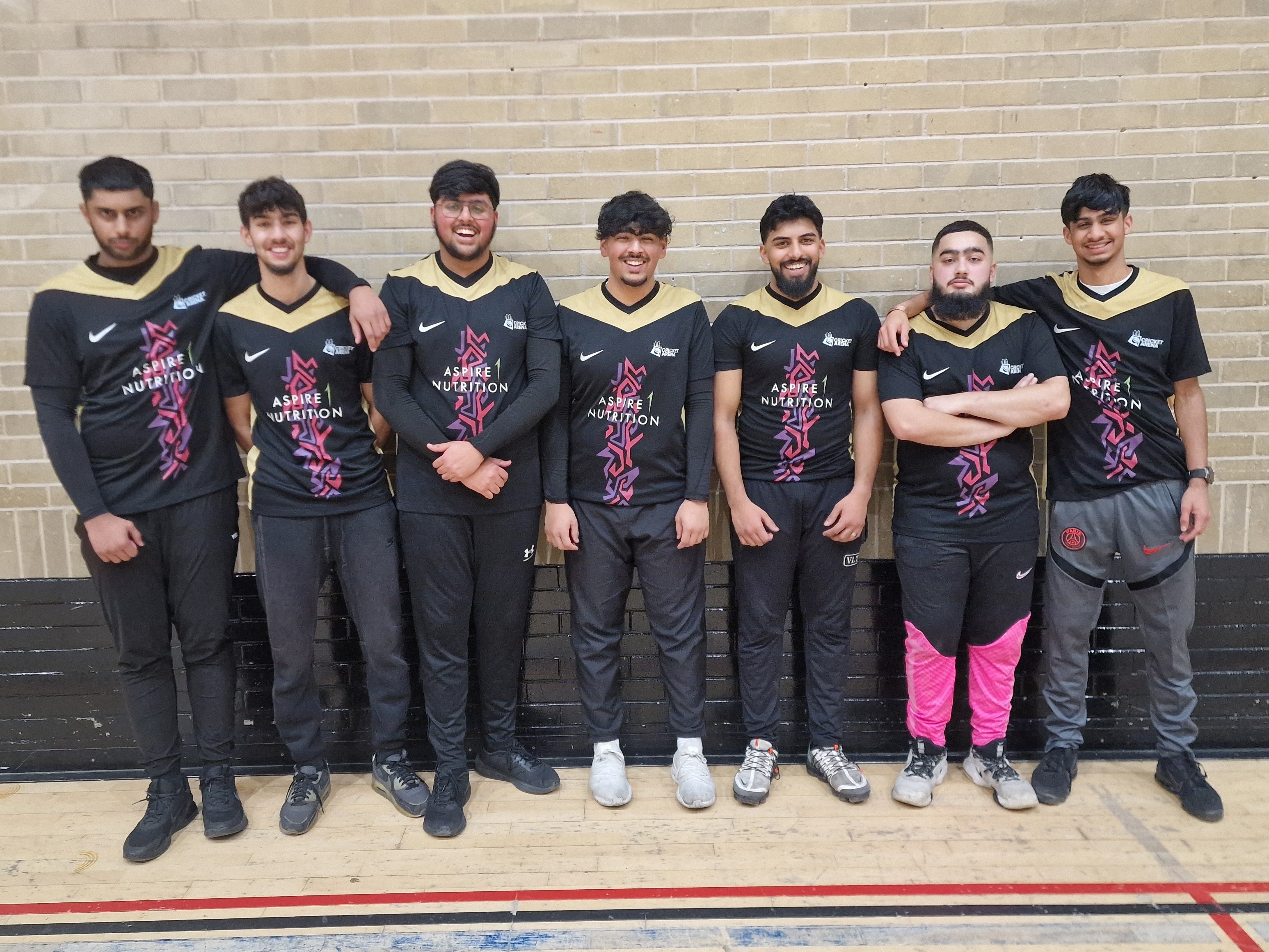 Sharrow Stars youth indoor cricket team in black and gold Aspire 1 Nutrition Nike shirts line up against a sports hall wall at Cricket Arena in Sheffield.
