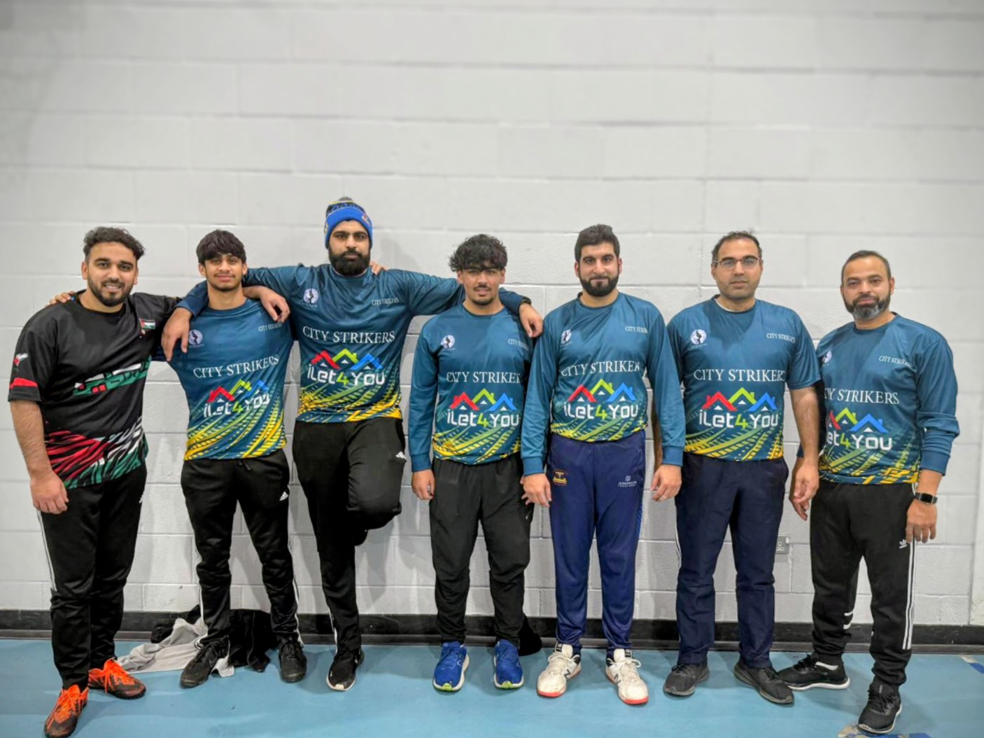 City Strikers City Sixes team pose together in blue iLet4u shirts during BBICL 2024, showing friendship and community indoor cricket in Sheffield.