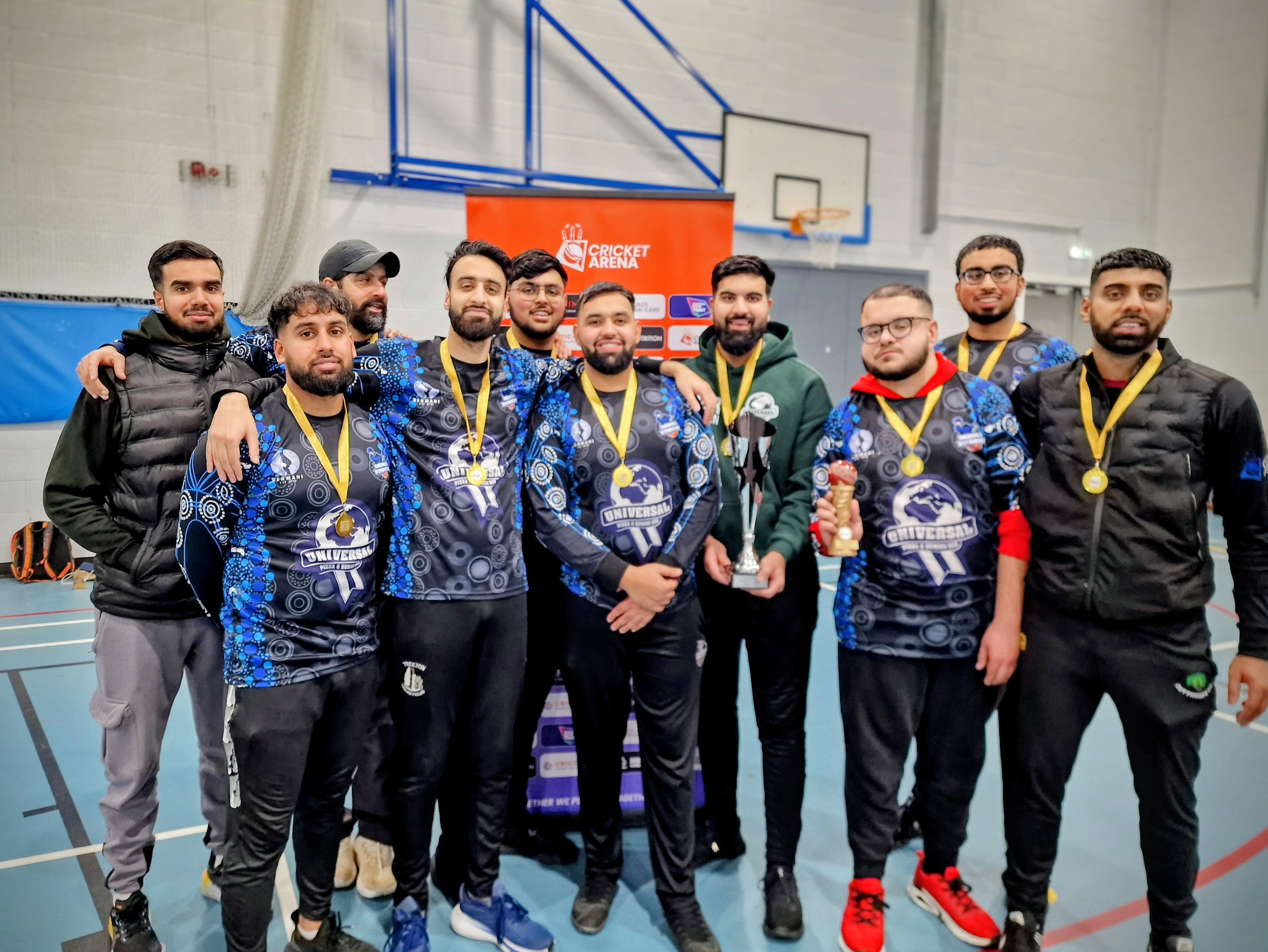 Darnall Dynamites celebrate with a representative from kit sponsor Universal Pizza & Burger Bar after BBICL 2024, holding trophies and medals in Sheffield.