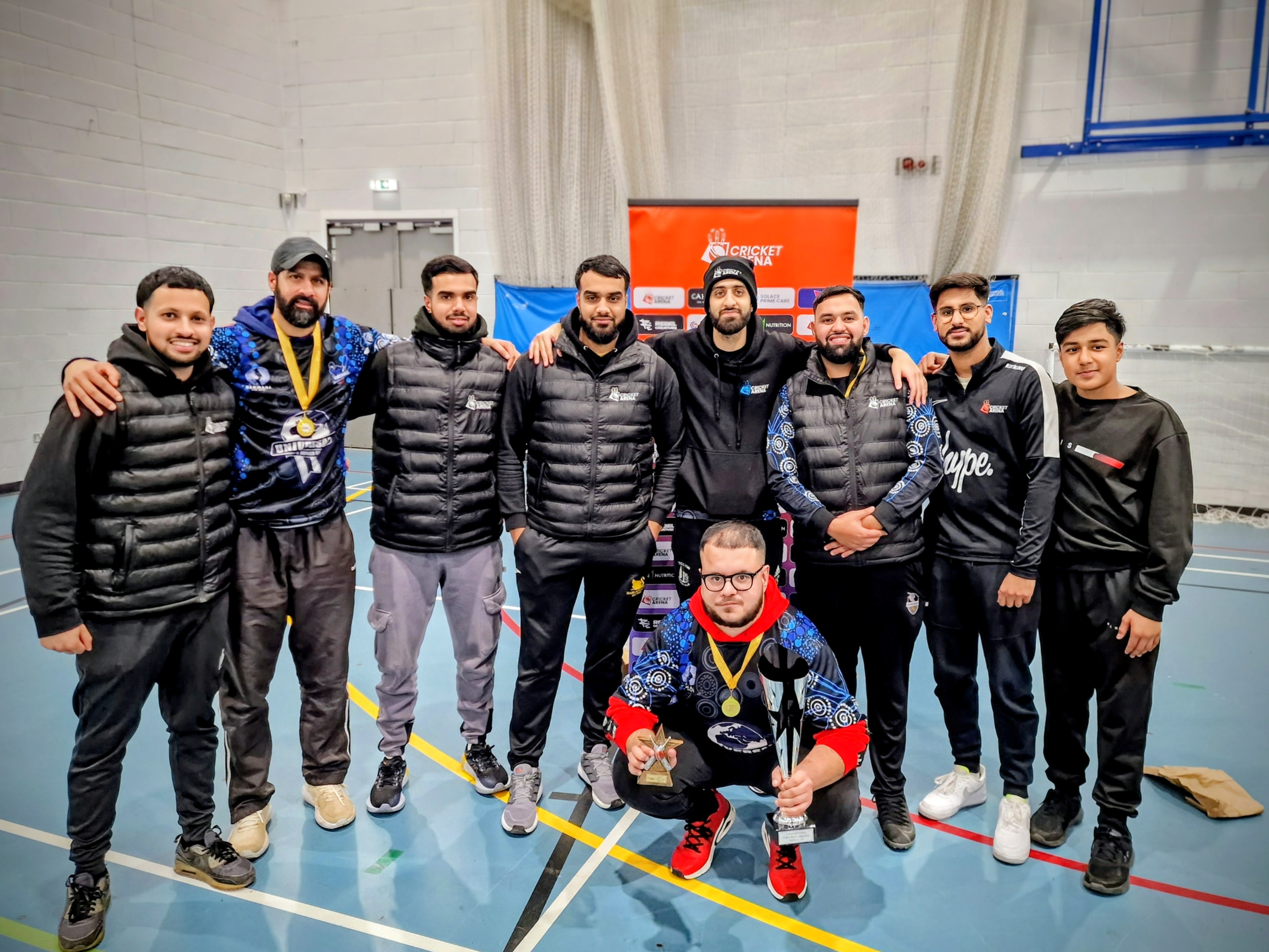 League volunteers and umpires pose together after BBICL 2024, wearing gilets and jackets to show the staff team behind the indoor cricket programme.
