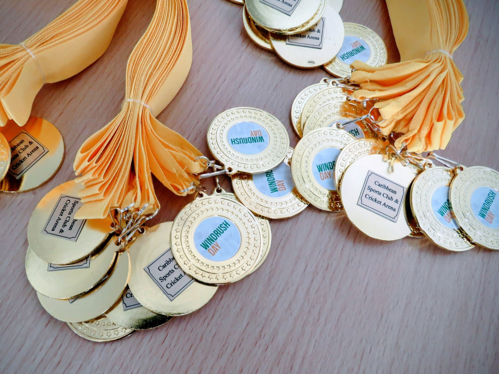 Gold Windrush Day medals with yellow ribbons prepared for participants at Caribbean Sports Club.