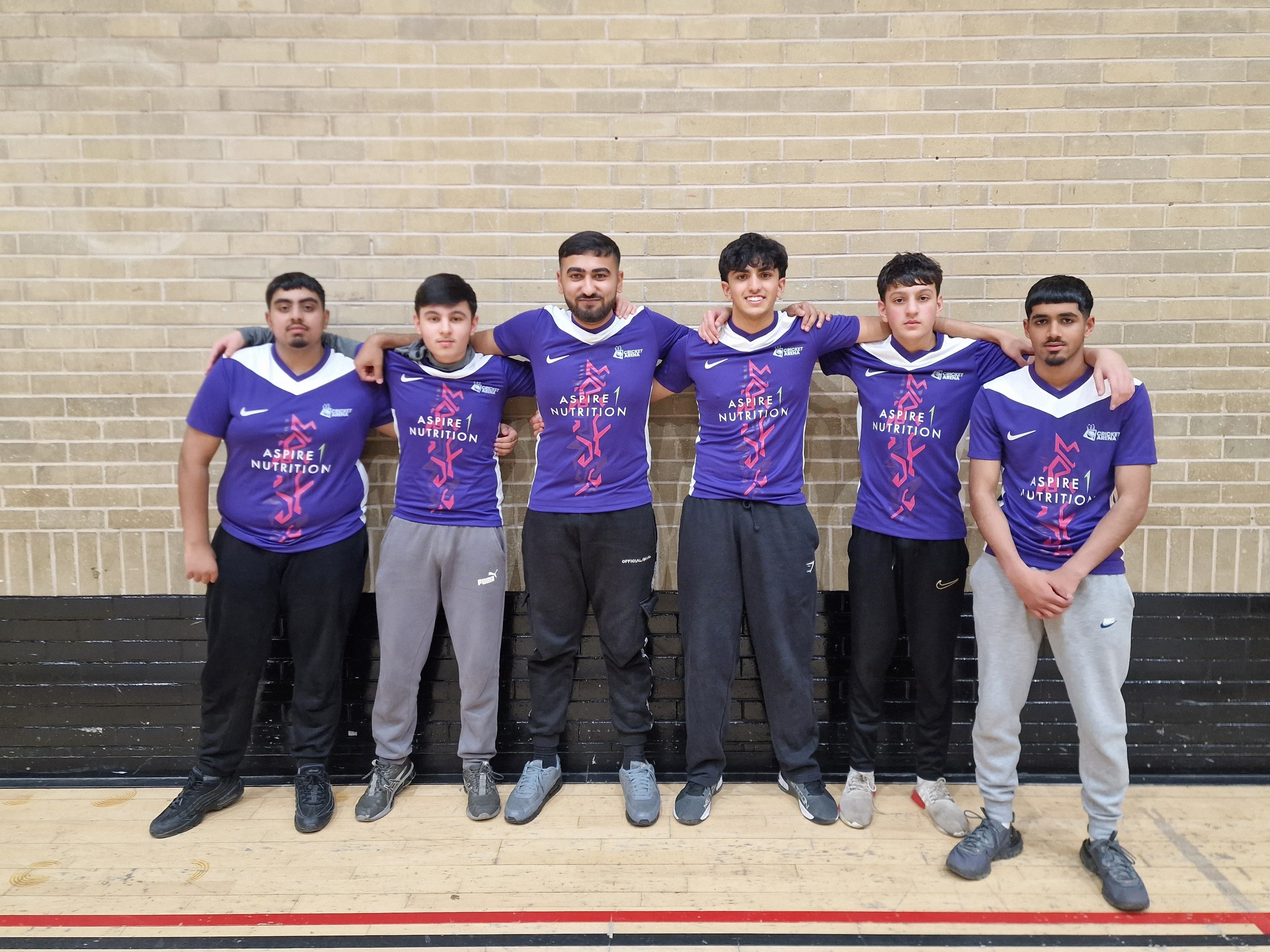 Six young players in matching Aspire 1 Nutrition shirts line up together during an MBL indoor cricket league night in Sheffield.