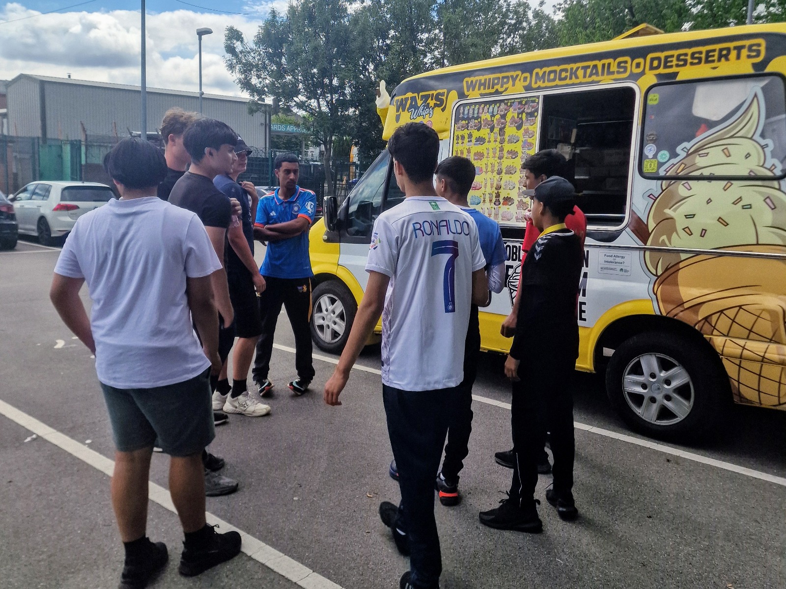 Junior Hundred 2025 players from different teams gather around an ice cream van after matches at Shiregreen Cricket Club in Sheffield.