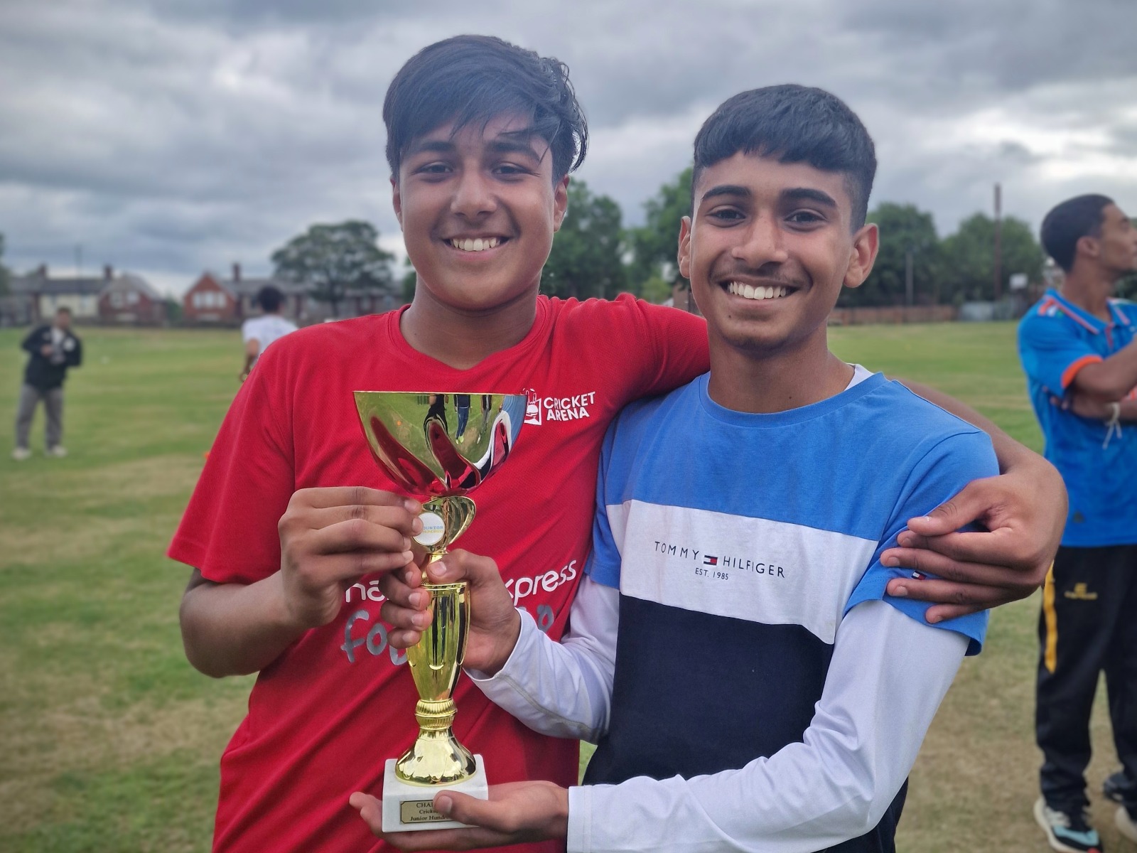 Two Junior Hundred 2025 finalist captains smile together holding a trophy, showing friendship between opposite teams at Shiregreen Cricket Club in Sheffield.