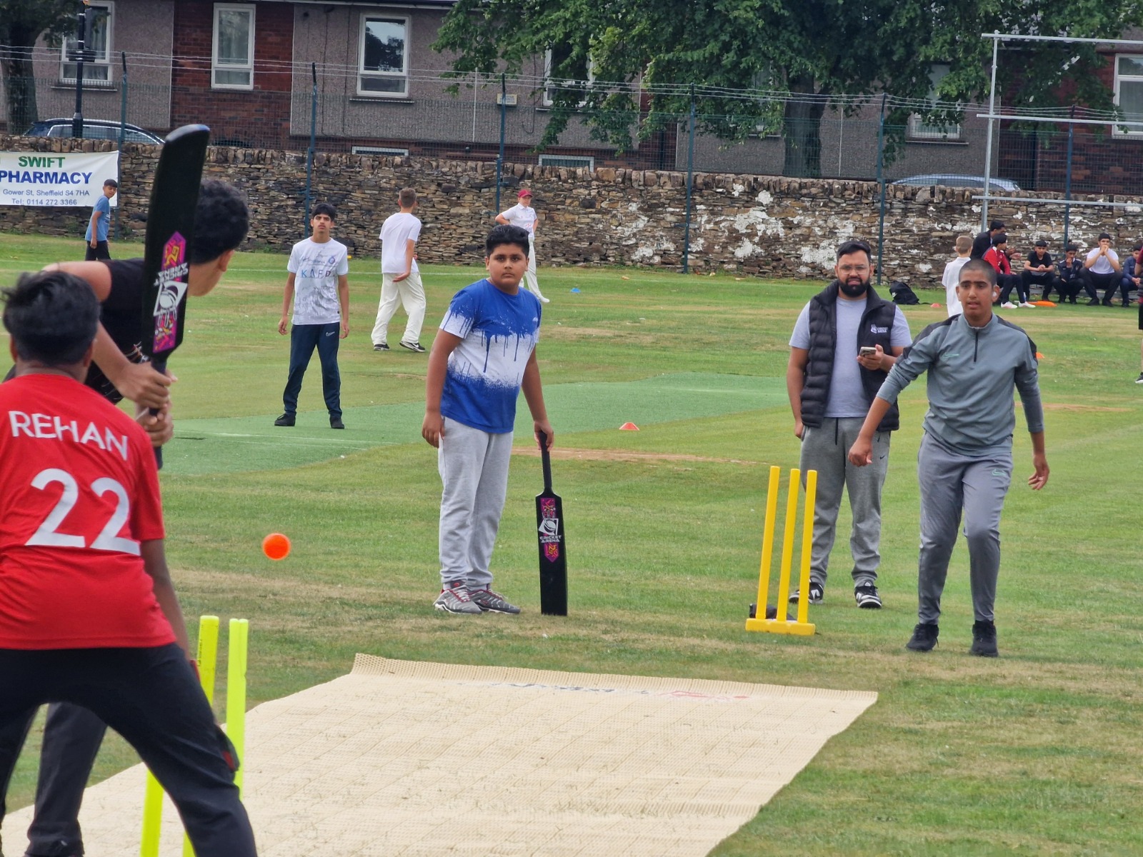 Junior Hundred 2025 soft-ball match at Shiregreen Cricket Club with a young bowler running in, batter set to hit and a coach watching from close by.