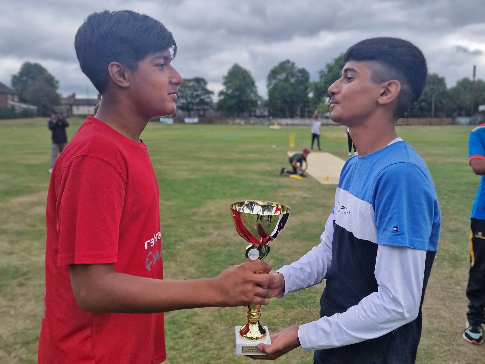 Two Junior Hundred 2025 finalist captains face each other holding the match trophy at Shiregreen Cricket Club in Sheffield.