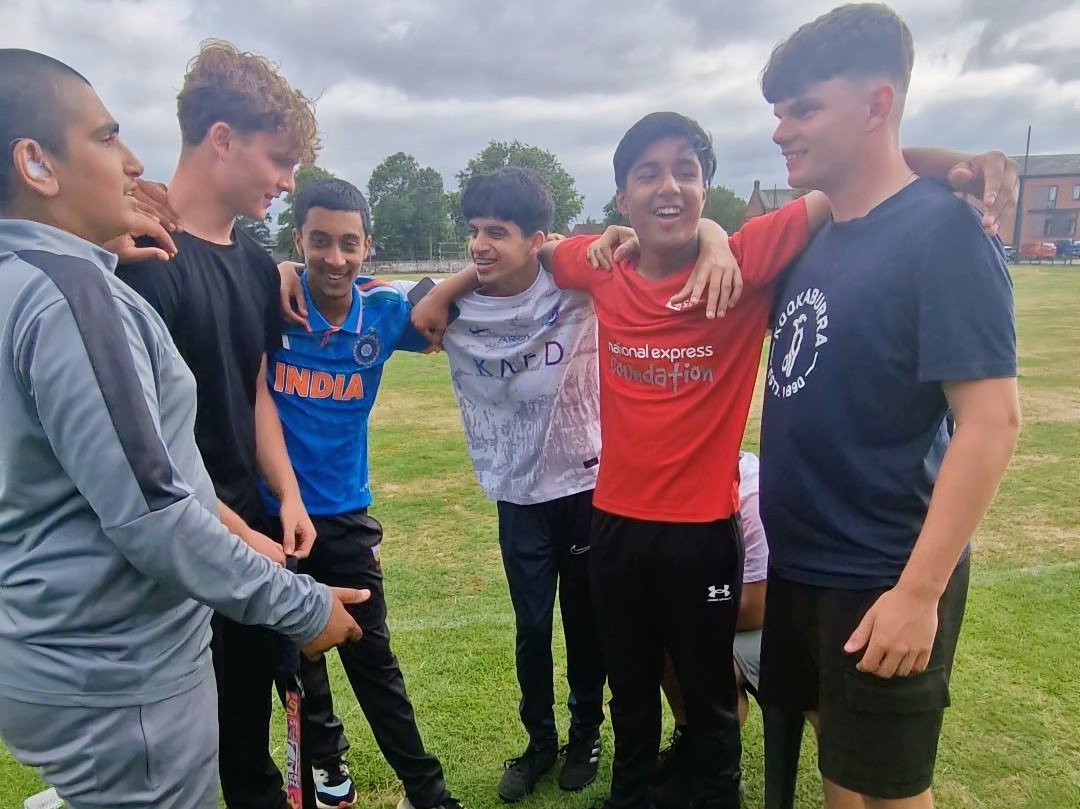 Sharrow Stars junior players stand arm in arm in a team huddle during Junior Hundred 2025 at Shiregreen Cricket Club in Sheffield.