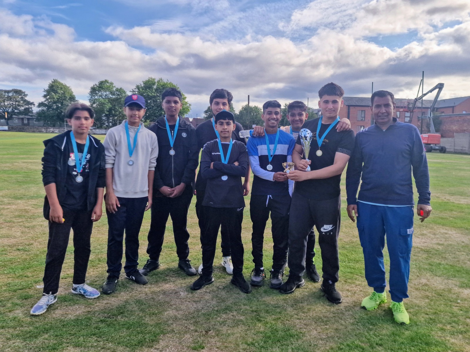 Shiregreen Lions runners-up team stand with medals and a finalist trophy alongside their coach after Junior Hundred 2025 in Sheffield.
