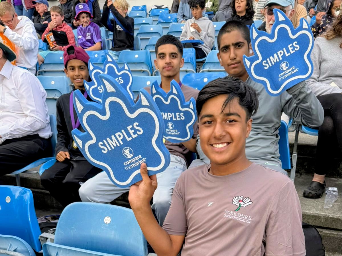 Young Sharrow Stars supporters hold blue foam Simples hands in the Headingley crowd during a Northern Superchargers Hundred match.