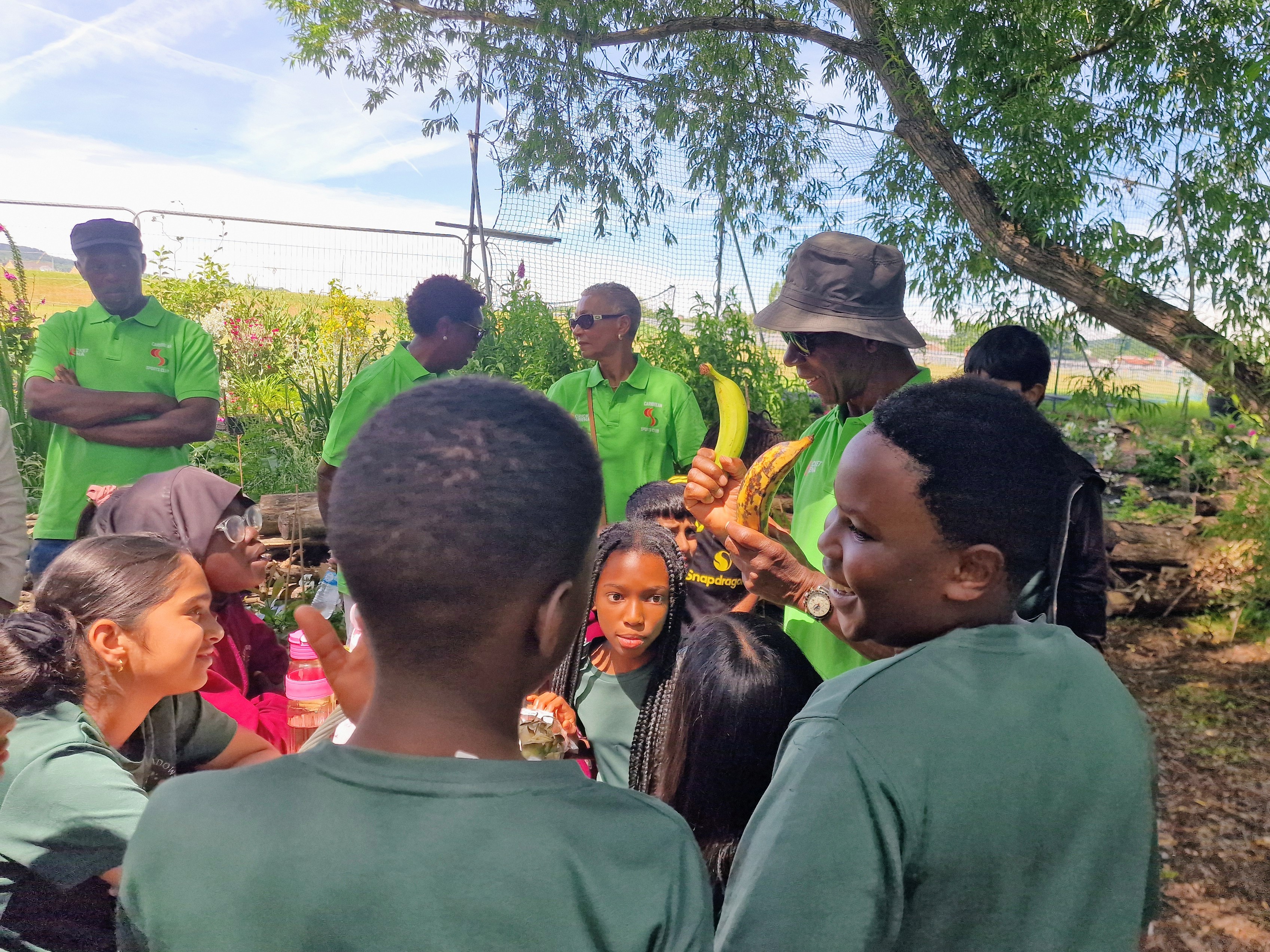 Children laugh as a club elder explains the difference between bananas and plantains in the Legacy Garden