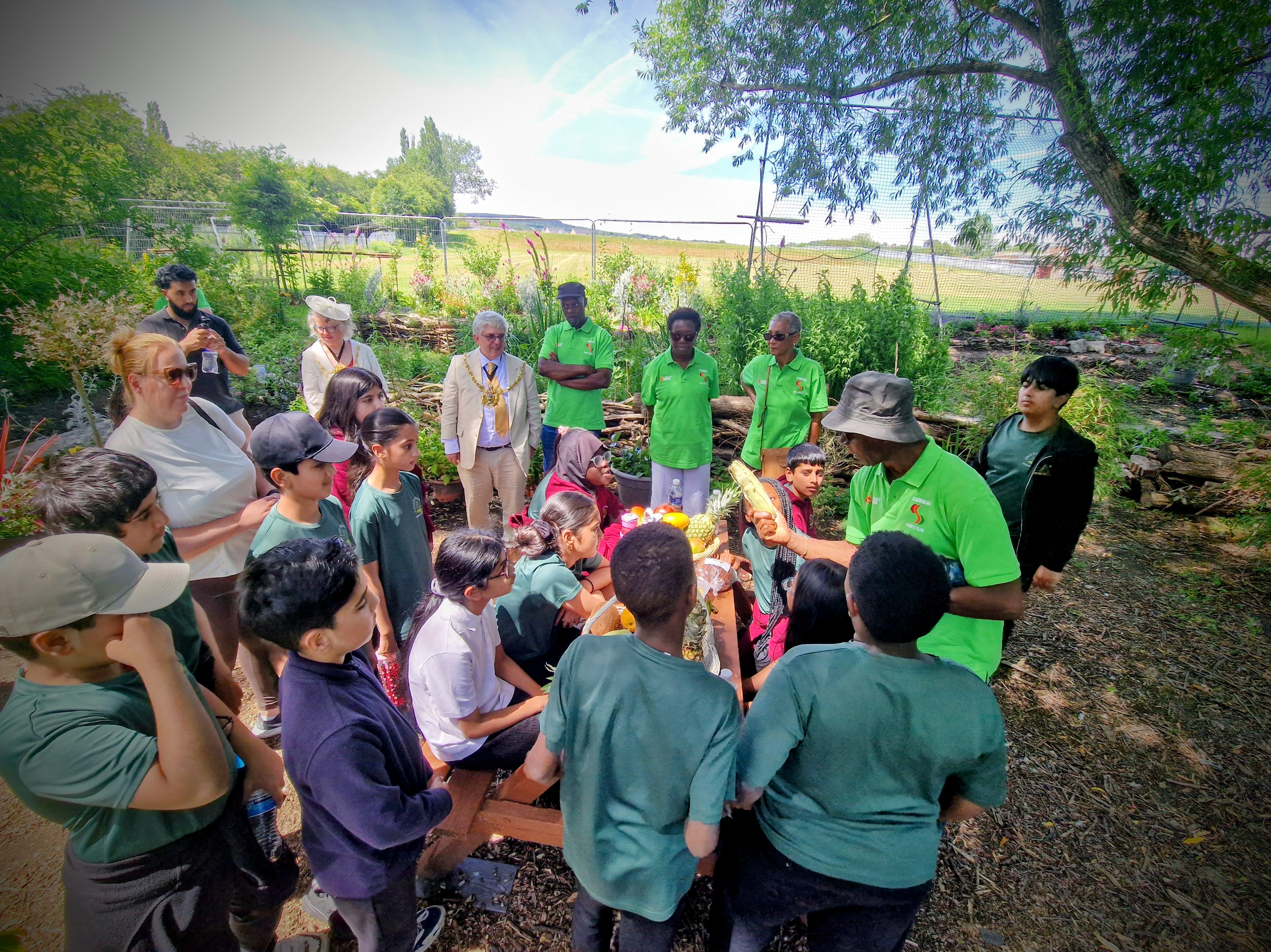 A club elder teaches children about Caribbean fruit in the Windrush Legacy Garden as the Lord Mayor of Sheffield looks on