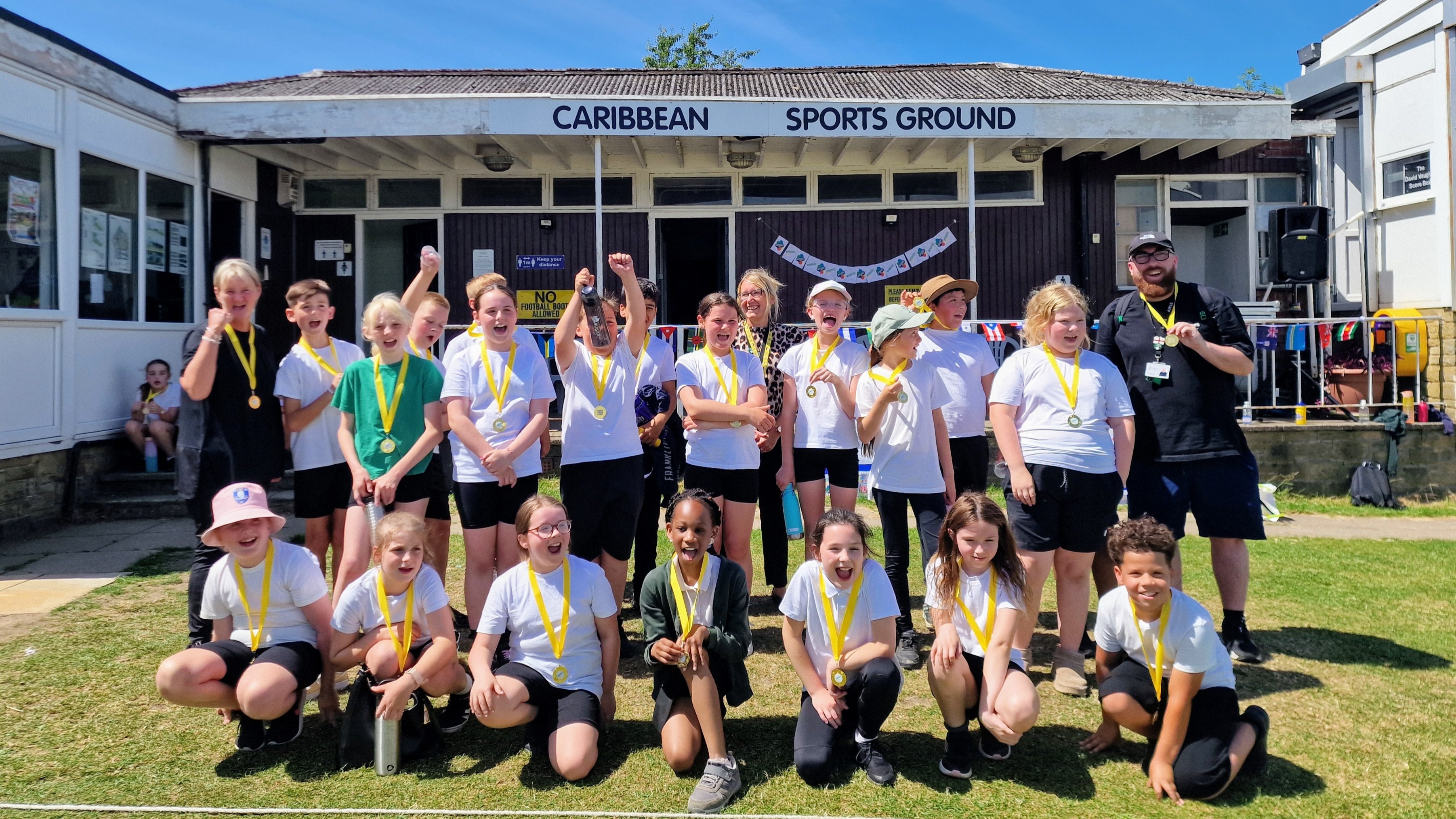 Schoolchildren cheer with their Windrush Day 2026 medals at Sheffield Caribbean Sports Club
