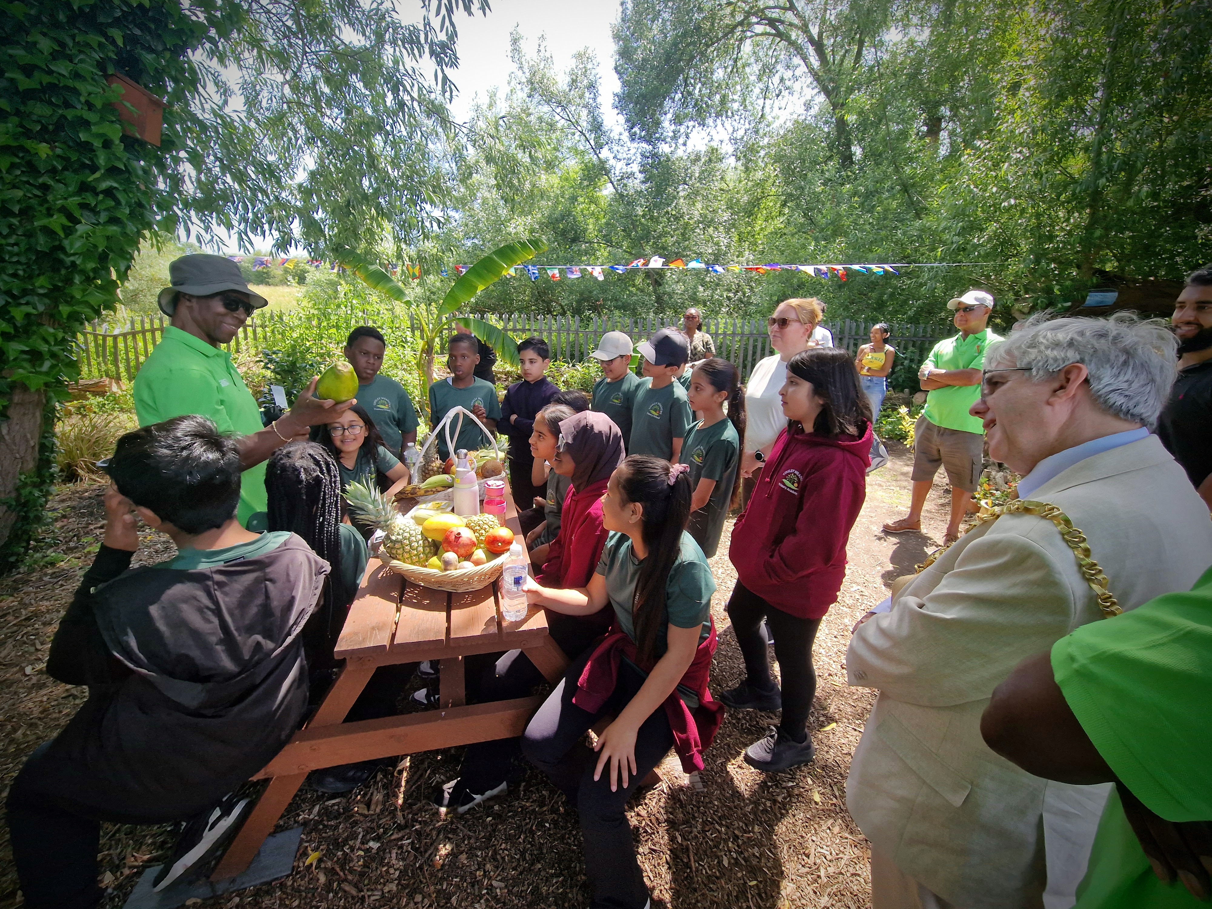 A club elder shows children a coconut in the Legacy Garden, sharing Caribbean heritage with visiting Sheffield schools