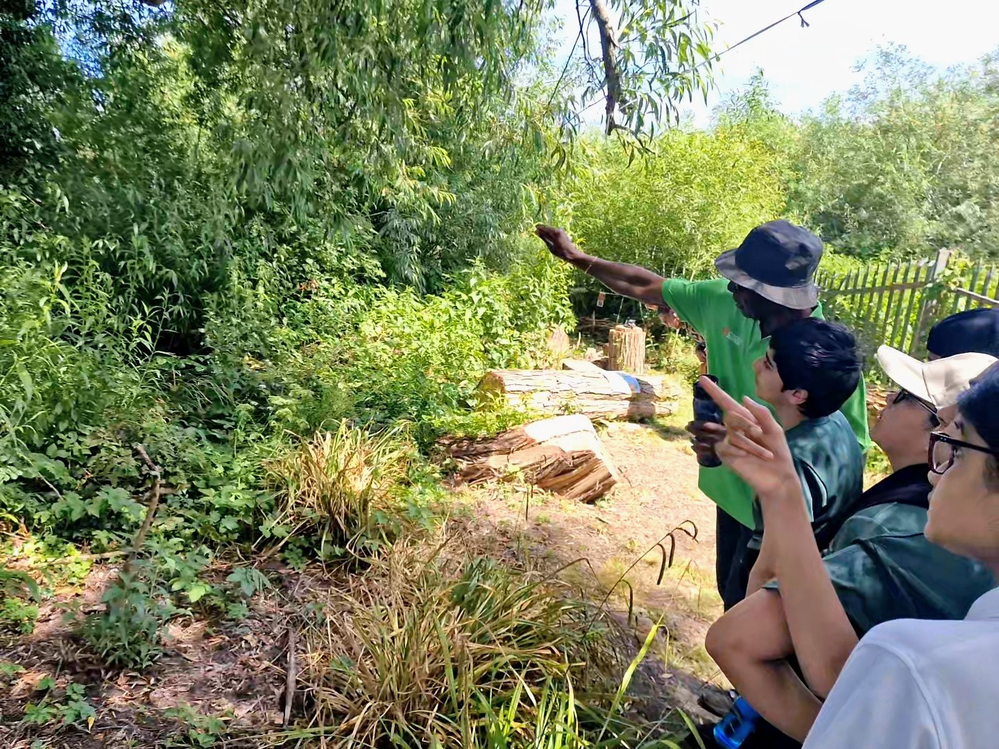 Children copy a club elder pointing out sights in the Windrush Legacy Garden, full of energy and curiosity