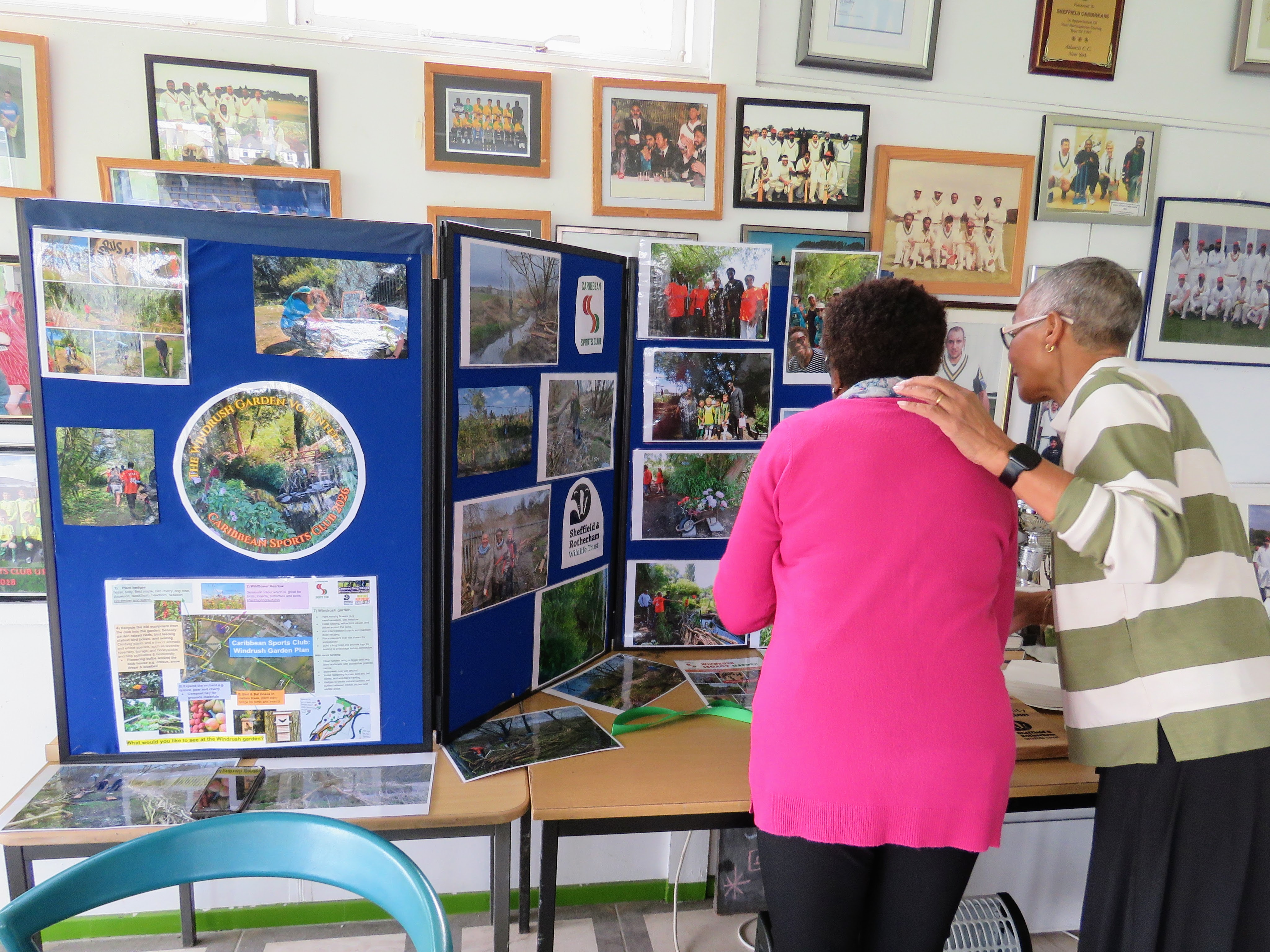 Visitors share memories over the Windrush Legacy Garden display boards in the Caribbean Sports Club clubhouse
