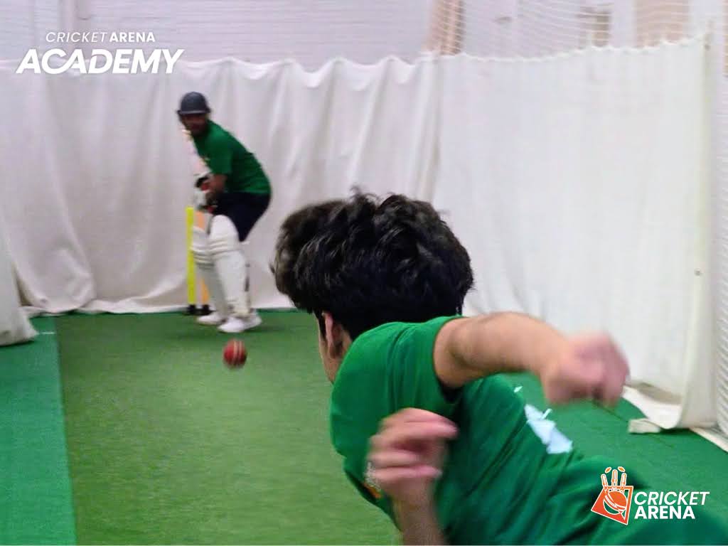 Close on a young bowler in his delivery stride at Cricket Arena Academy in Sheffield, hardball intensity inside an all-weather indoor centre.