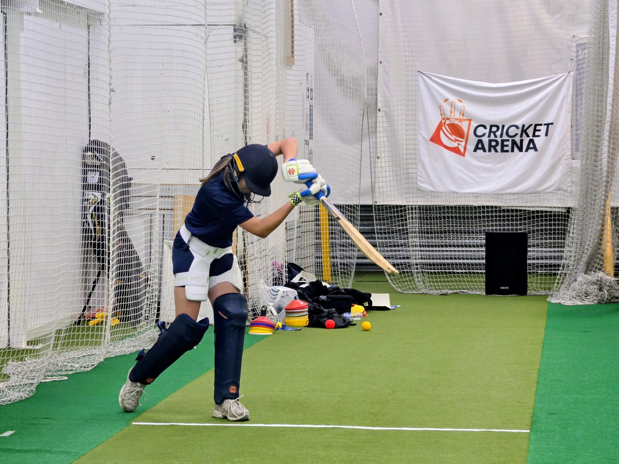 A Girls Academy batter plays a full drive in the Sheffield indoor nets, hardball skills built over an eight-week block.