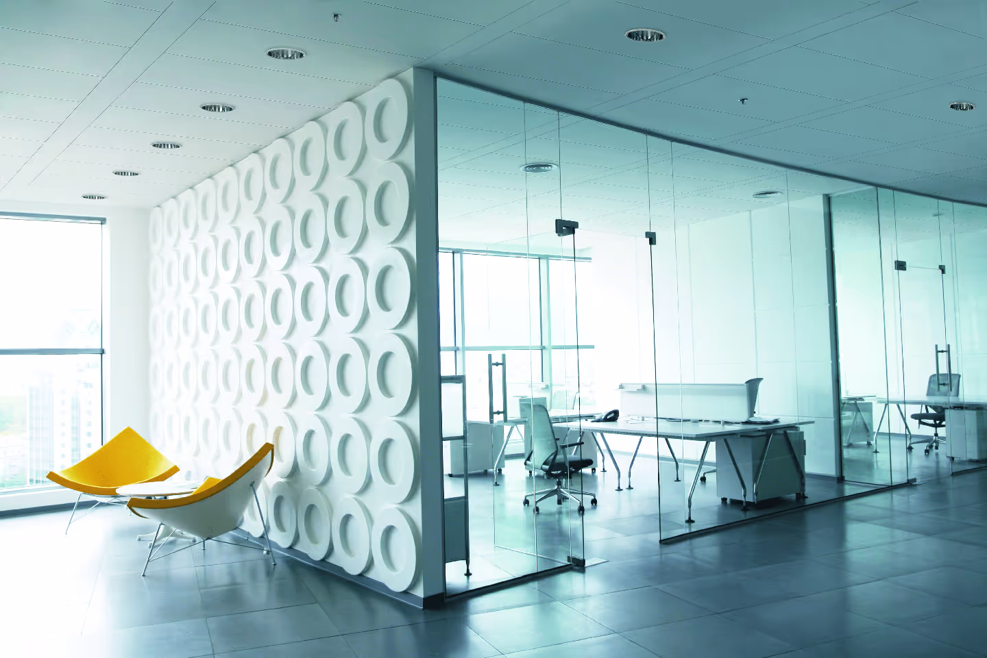 Modernes Büro mit einer eleganten QLIMATE-Bandrasterdecke, bei der lange, schmale Deckenelemente eine ruhige Linienstruktur bilden und die Klimafunktion unauffällig integriert ist.