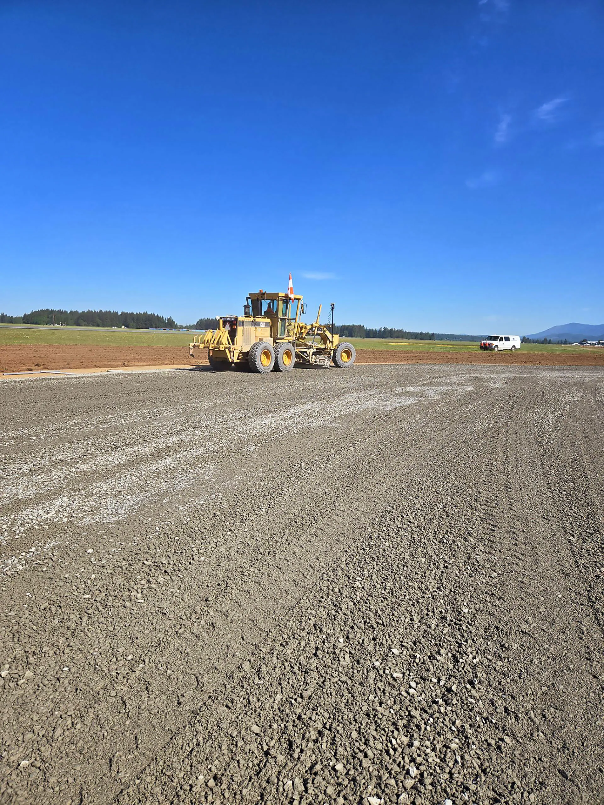 A yellow tractor is driving on a dirt road.