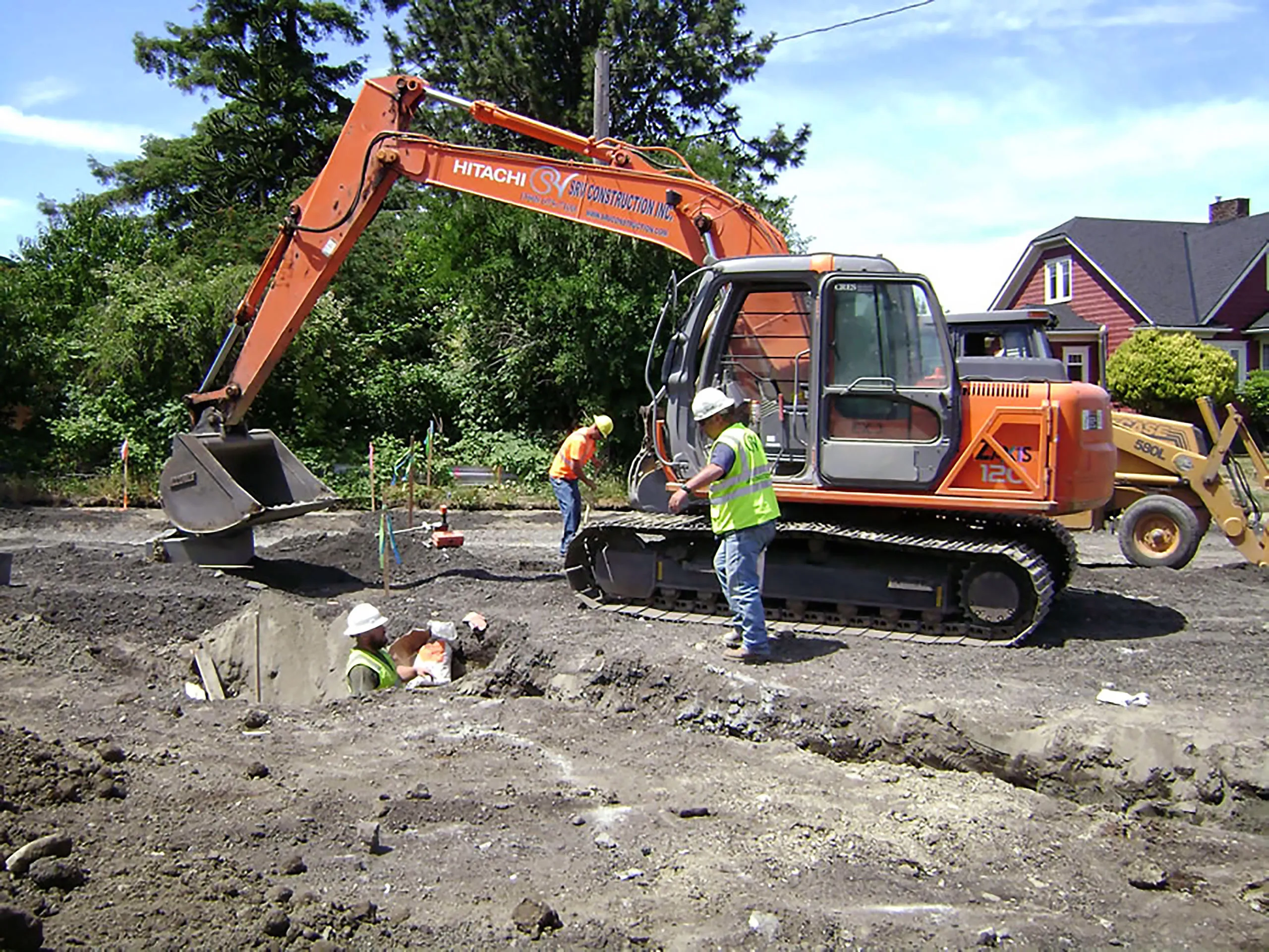 A large orange excavator is digging a hole in the ground.