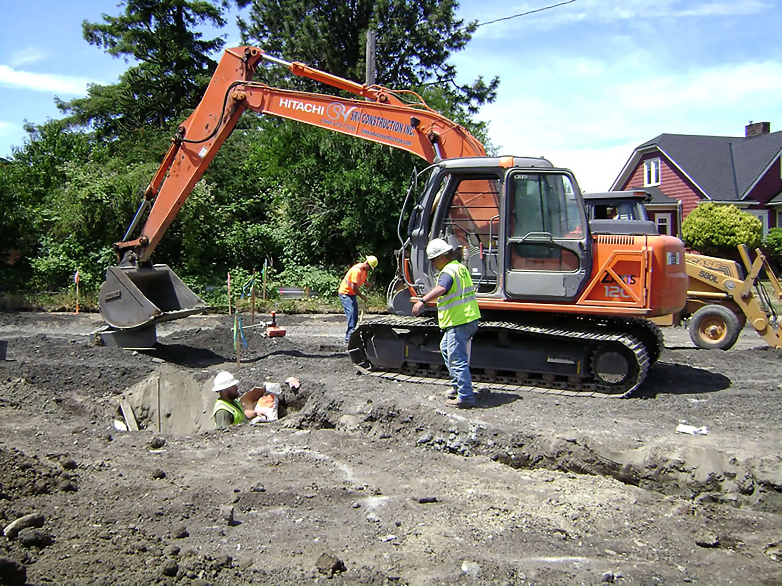 A large orange construction machine is digging a hole in the ground.