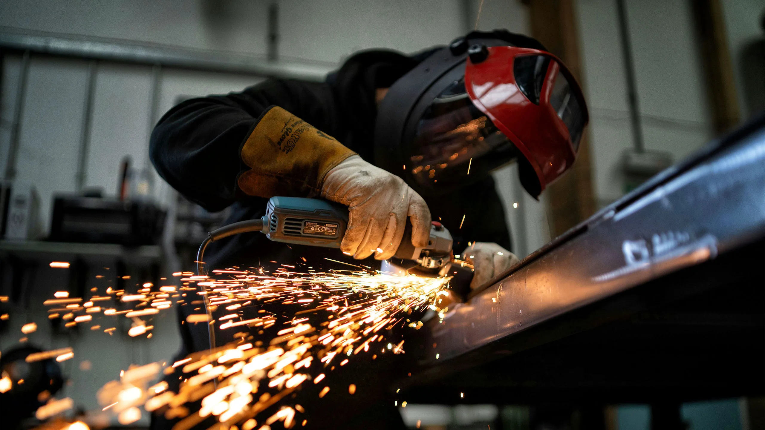 A man wearing a helmet and gloves is welding metal.