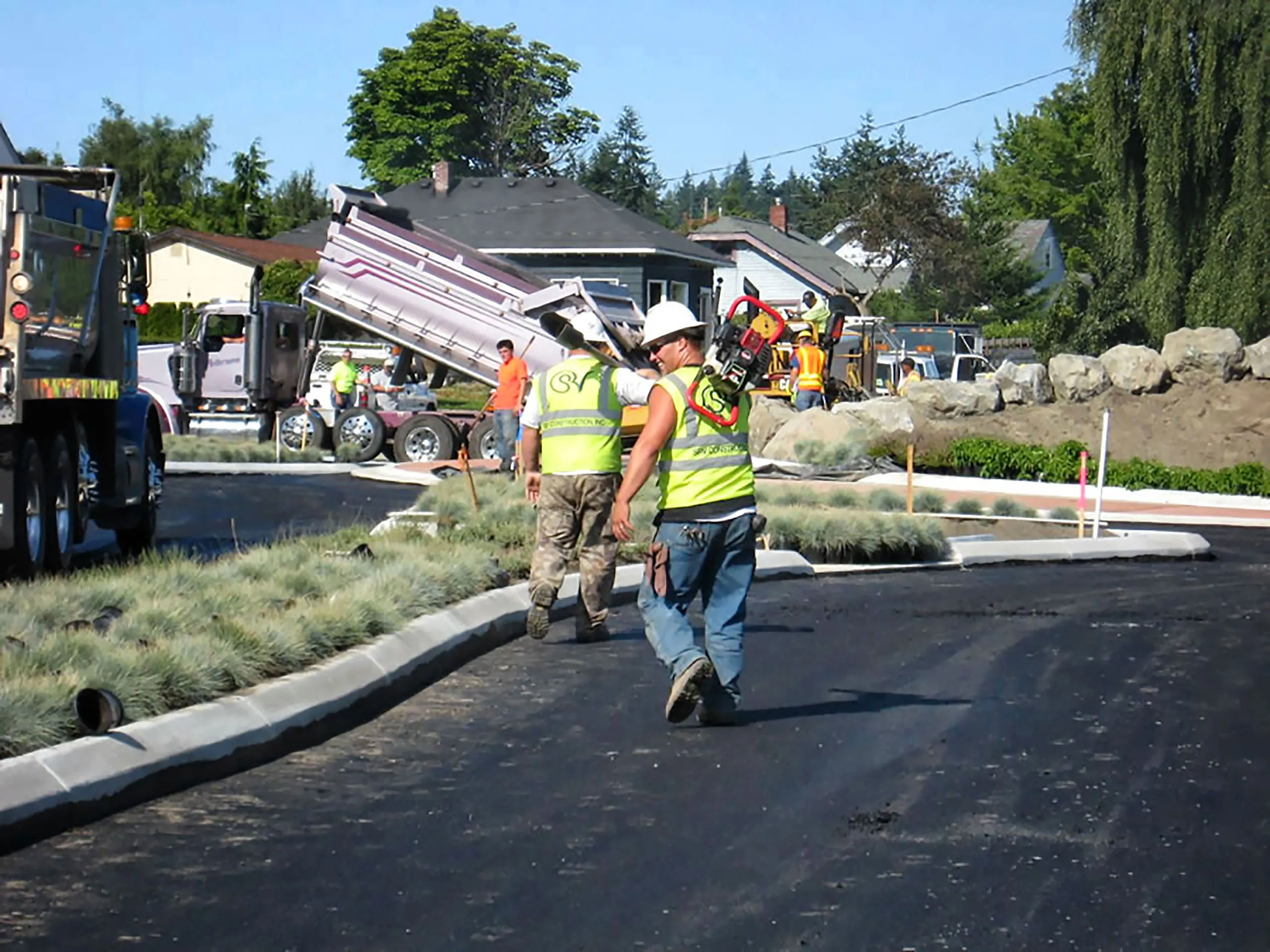 A man in a yellow vest is walking on a road.