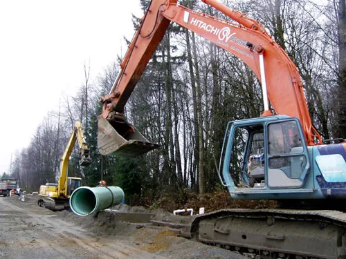 A Hitachi excavator is digging a trench.