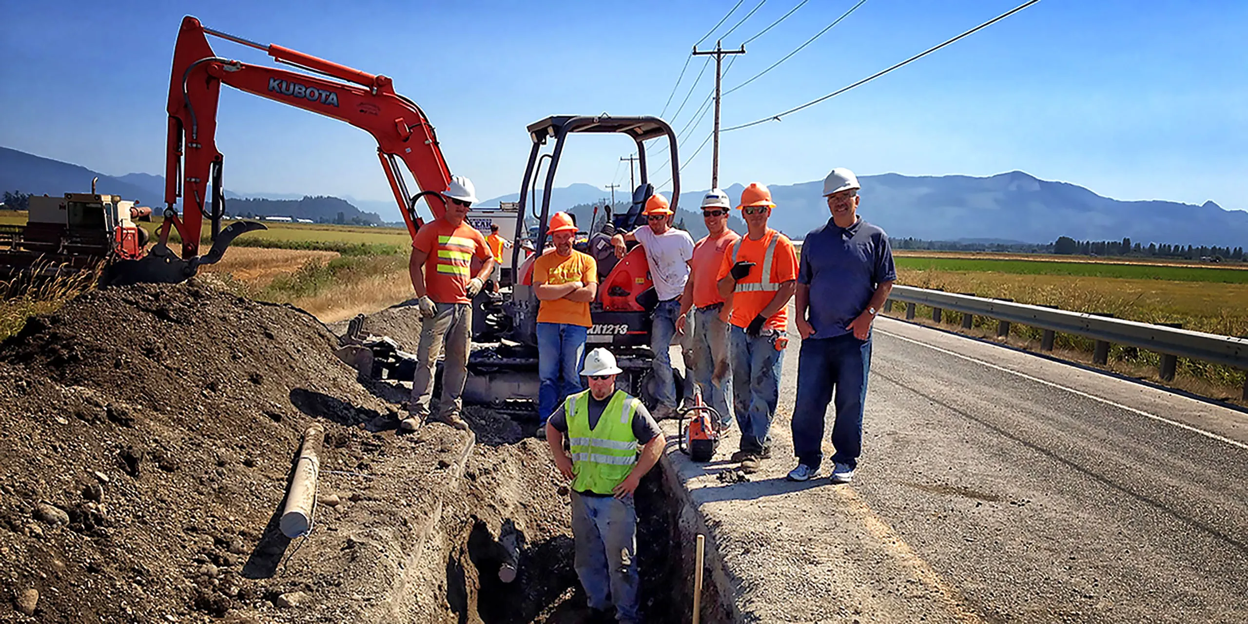 A group of construction workers standing in front of a digger.