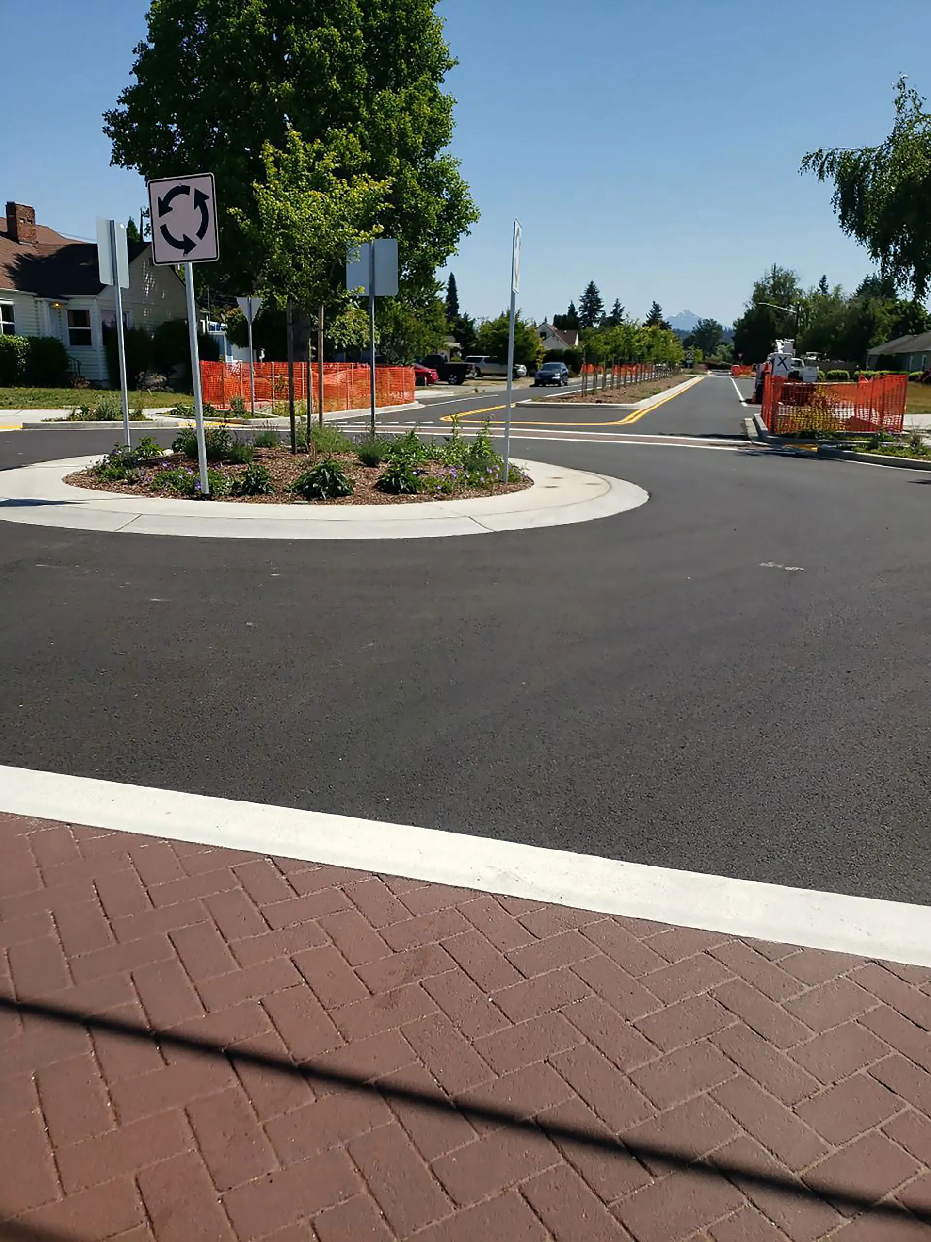 A brick roadway with a circular sign and a roundabout.