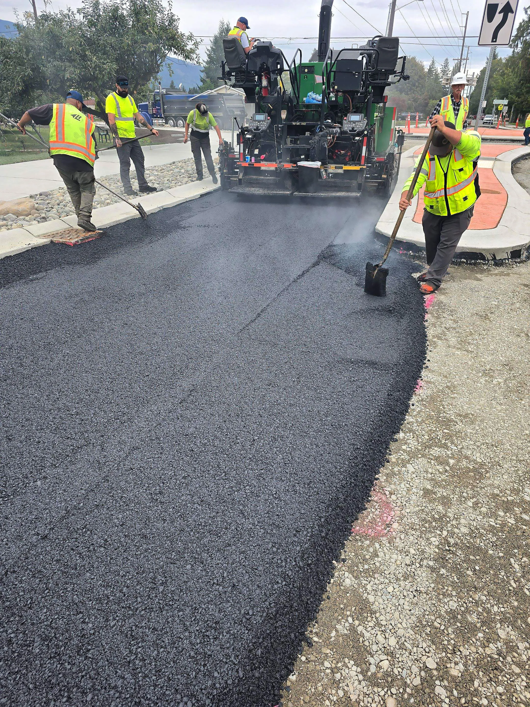 A man is shoveling asphalt on a road.