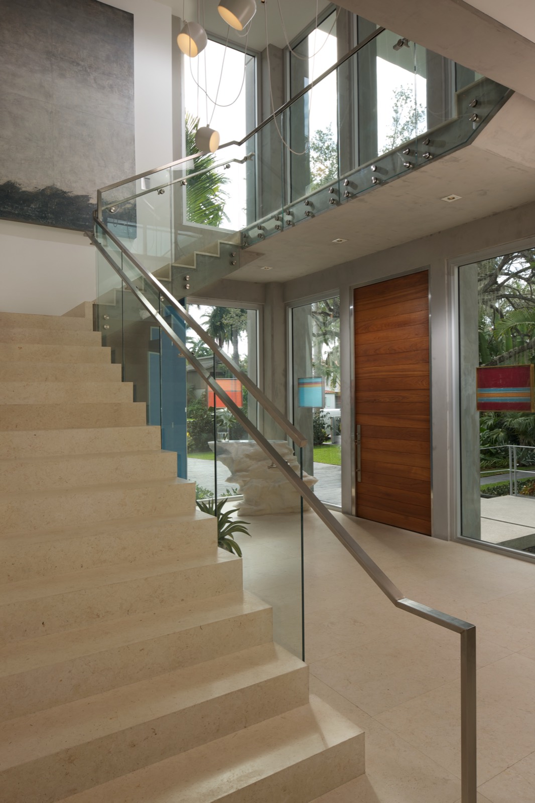 Large wood pivot entry door amid full-height glazing