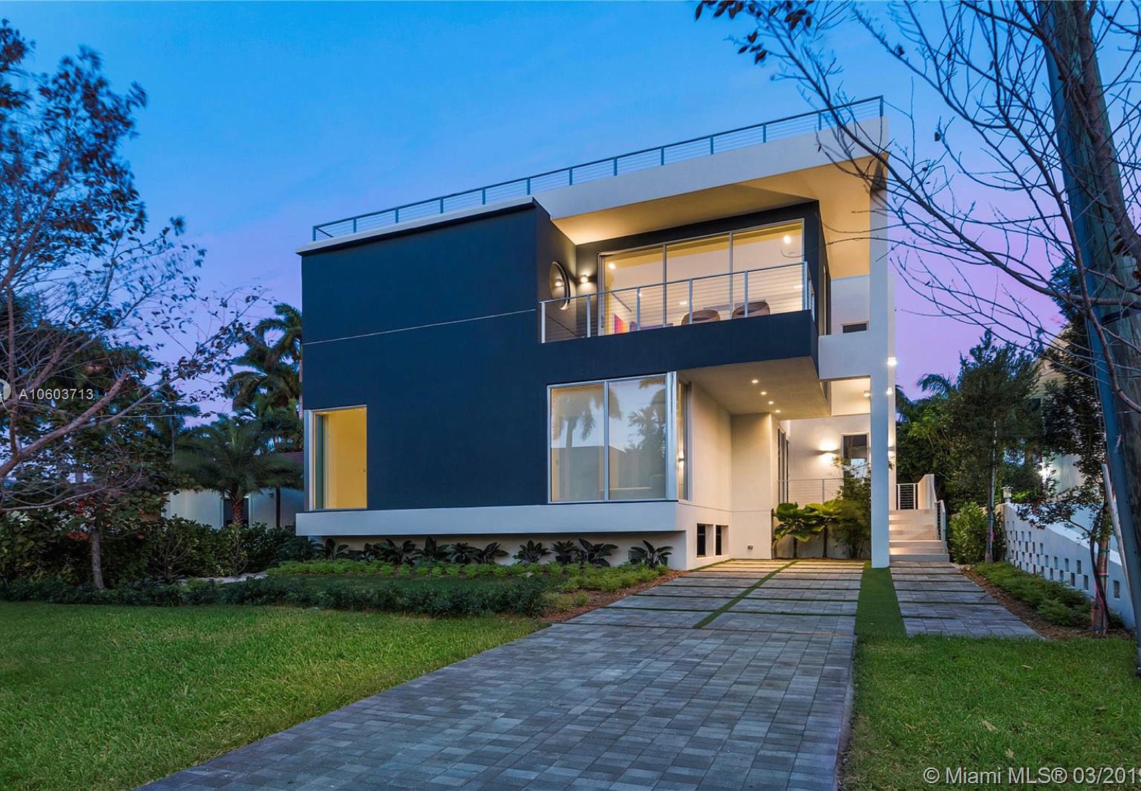 Modern Caribbean home exterior at dusk with floor-to-ceiling glass