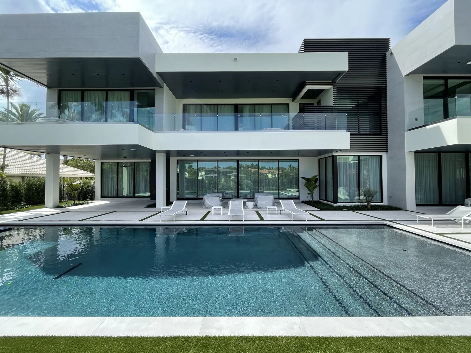 Slim-framed sliding glass walls on a waterfront pool facade