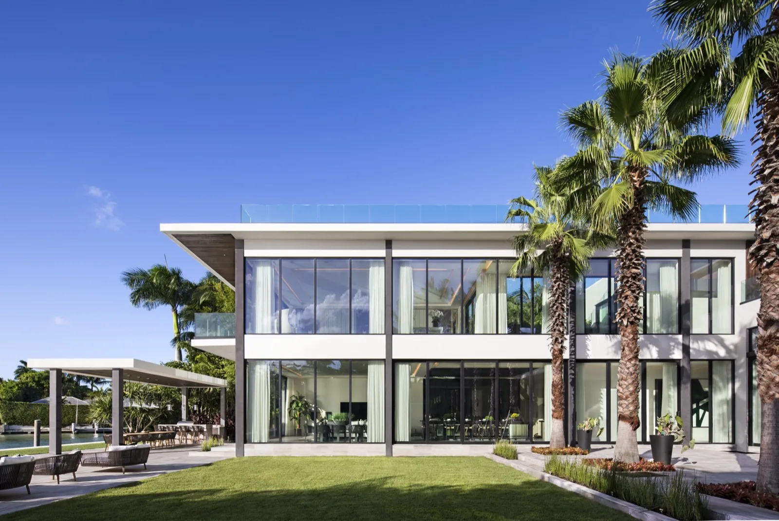 Two-story glass facade of a modern home over a lawn