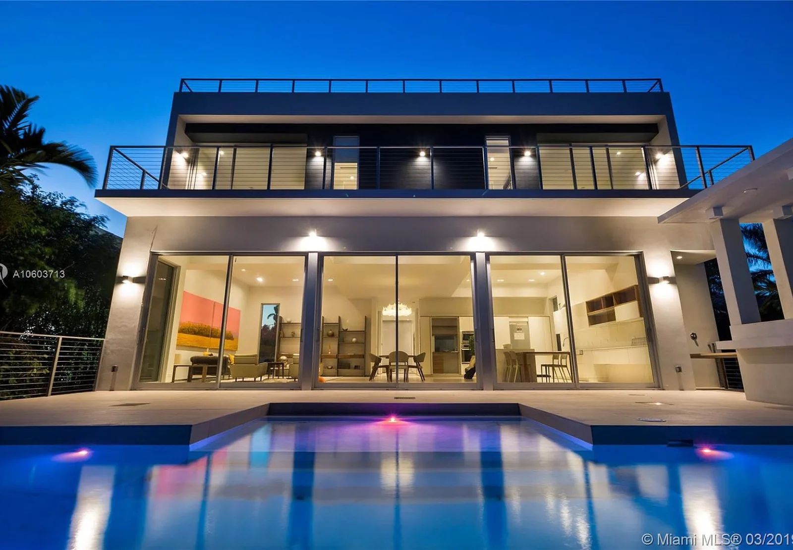 Multi-slide glass door wall open to a pool at dusk