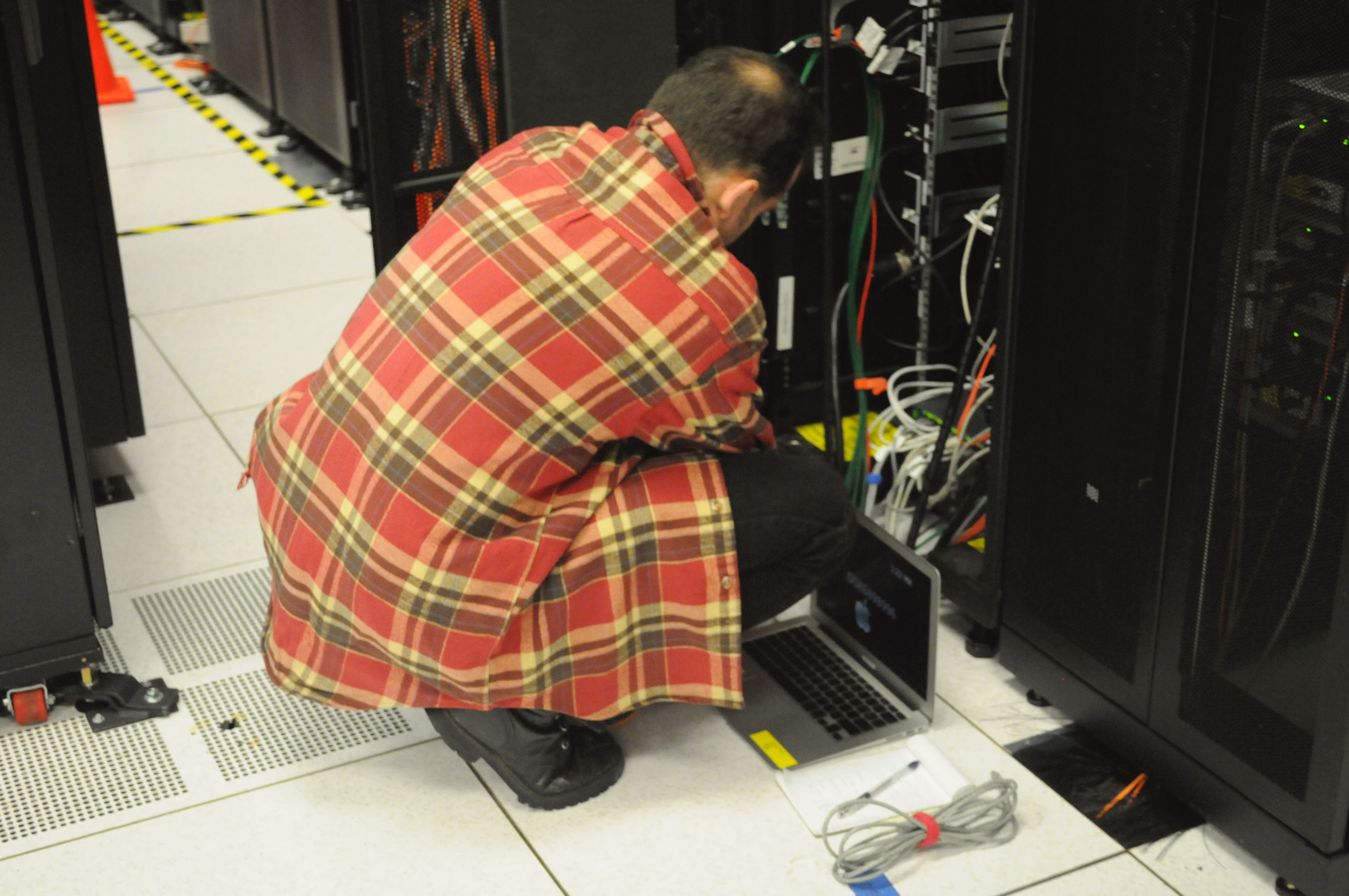 A technician working on a server rack in a data centre