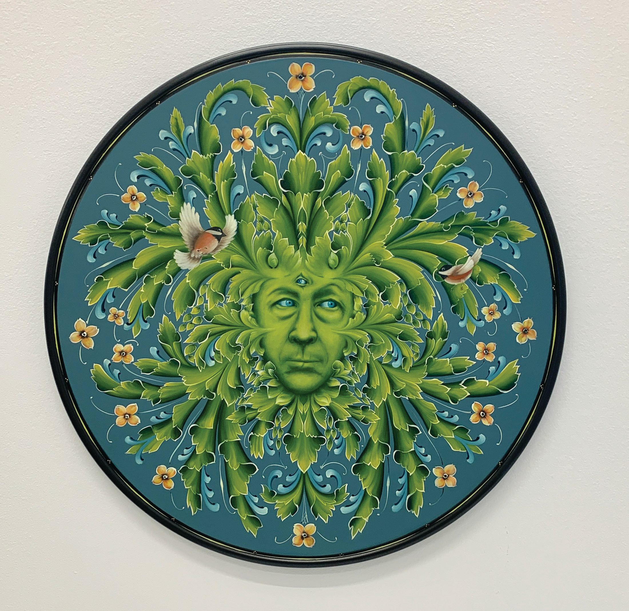 Greenman, a 2024 rosemaled plate by Jerry Johnson, a foliate face in green scrollwork on a deep blue ground, from the Nordic Echoes exhibition.